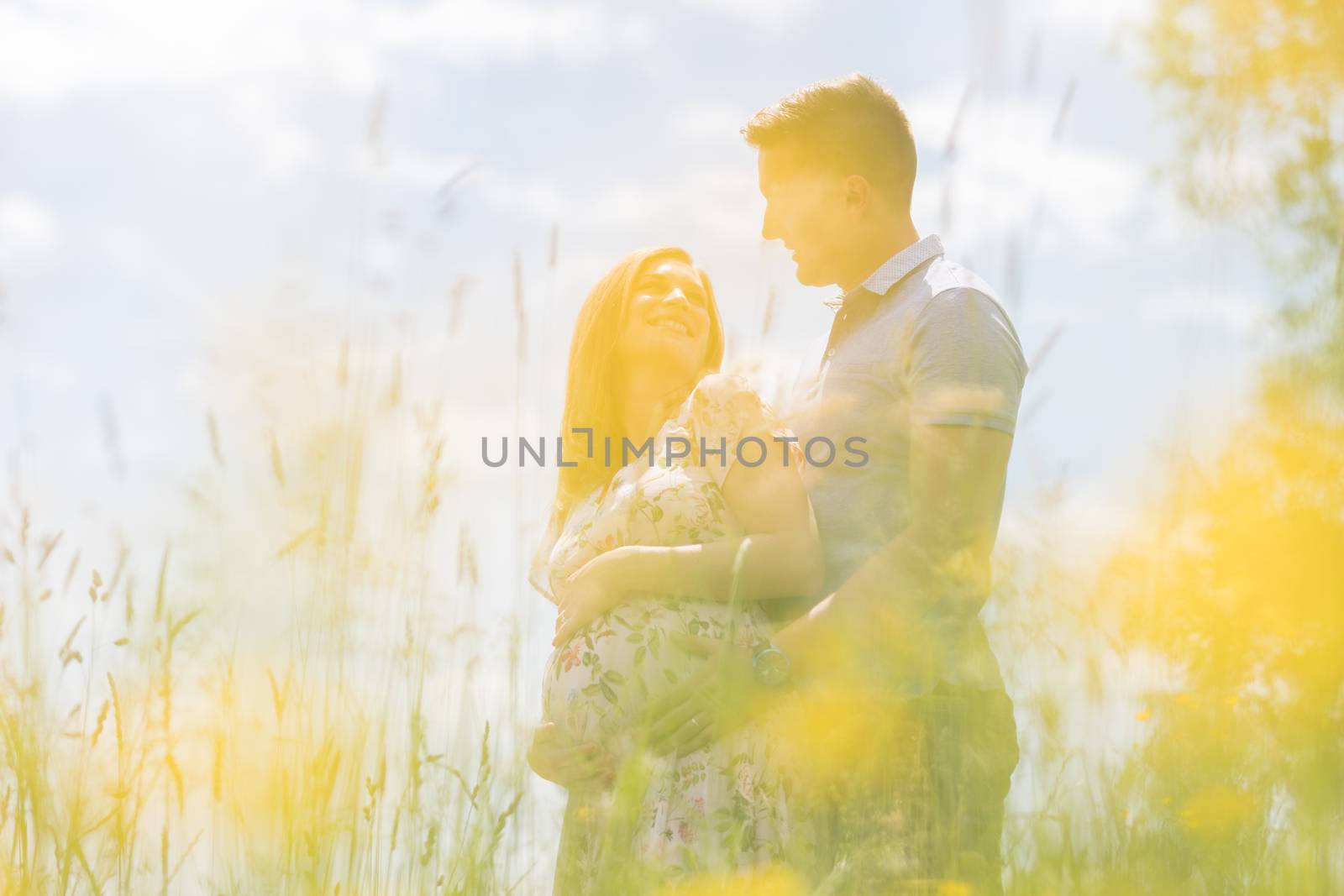 Young happy pregnant couple hugging in nature. Concept of love, relationship, care, marriage, family creation, pregnancy, parenting