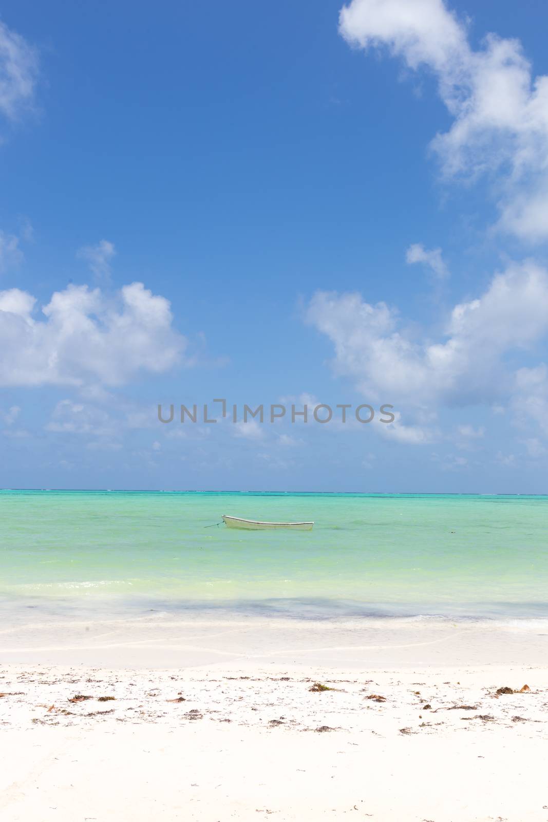 Solitary fishing boat on picture perfect white sandy beach with turquoise blue sea, Paje, Zanzibar, Tanzania. Copy space.