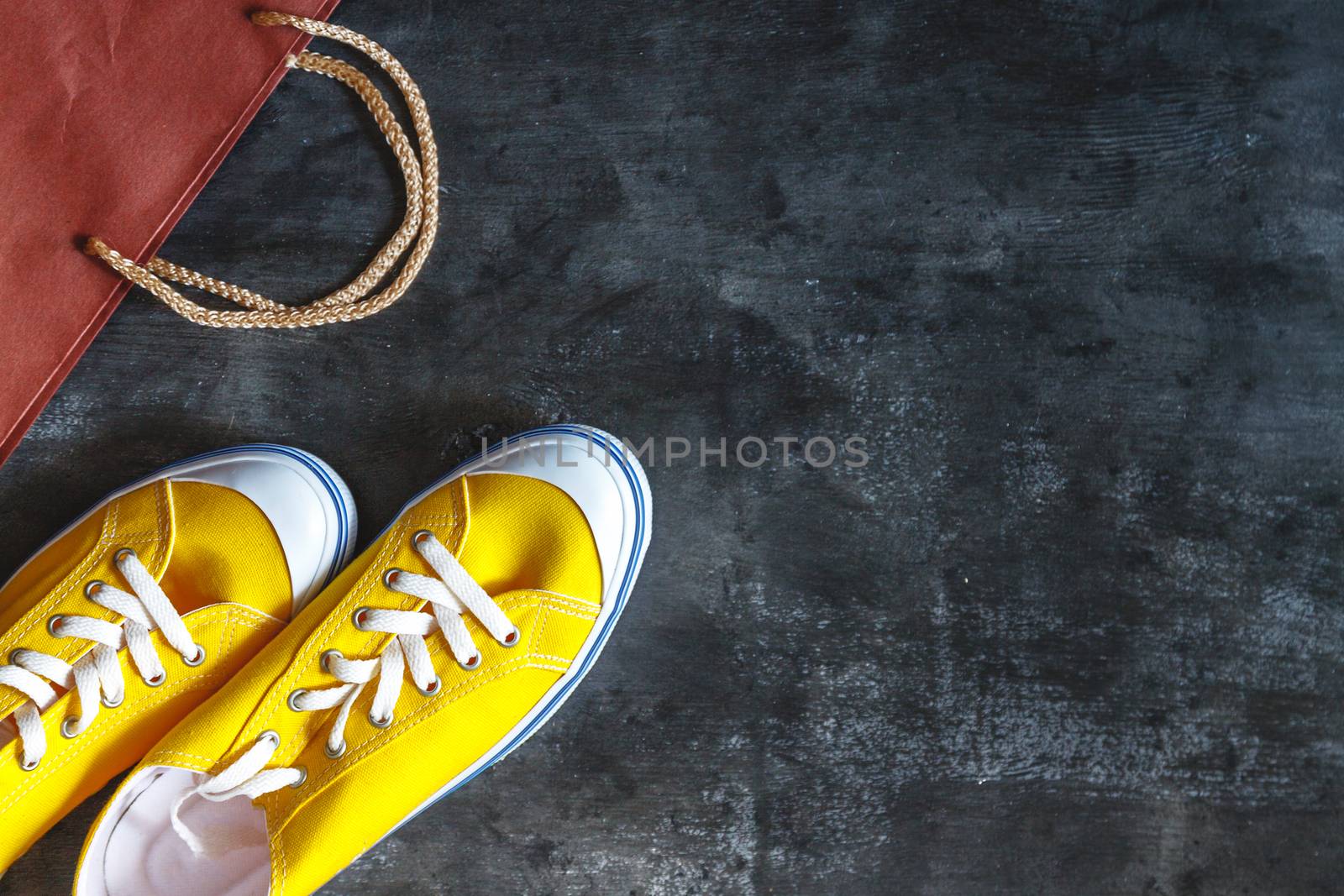 New yellow sneakers, box and package from the store on a dark concrete background. View from above. Copy space.