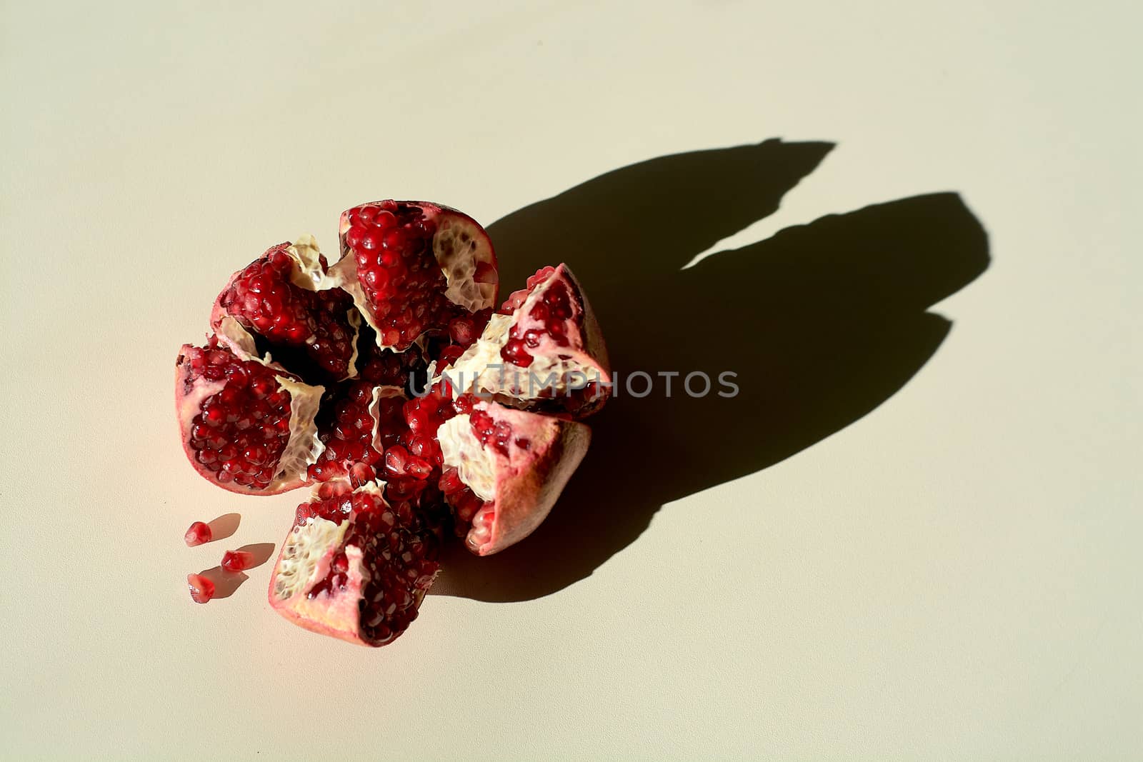 Garnet. Ripe red juicy pomegranate. Grains pomegranate fruit. Pomegranate cut in the form of a star. Lonely fruit on a light background. Hard daylight.