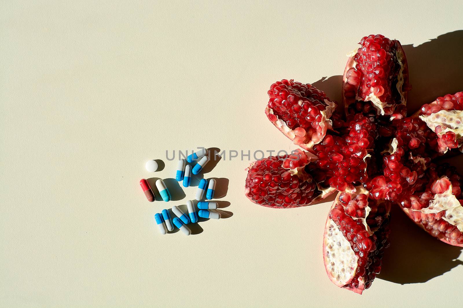 Garnet. Tablets and capsules, pills. The concept of a healthy life. Ripe red juicy pomegranate and pills, capsules, pills lying separately on a white background. Grains pomegranate fruit.