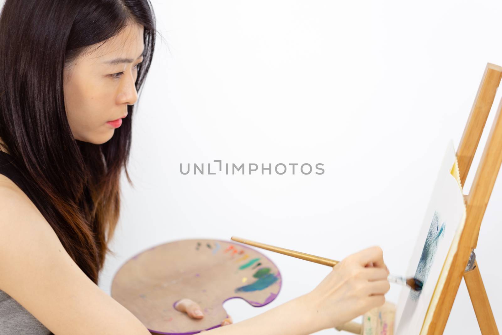 Asian American artist painting on an easel by imagesbykenny