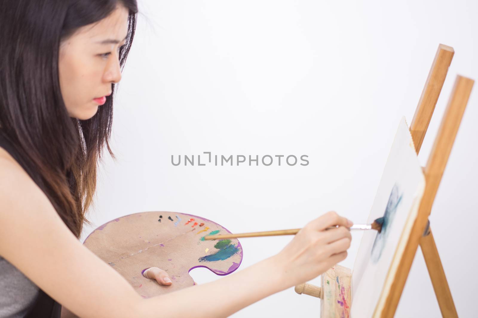 Asian American artist painting on an easel by imagesbykenny