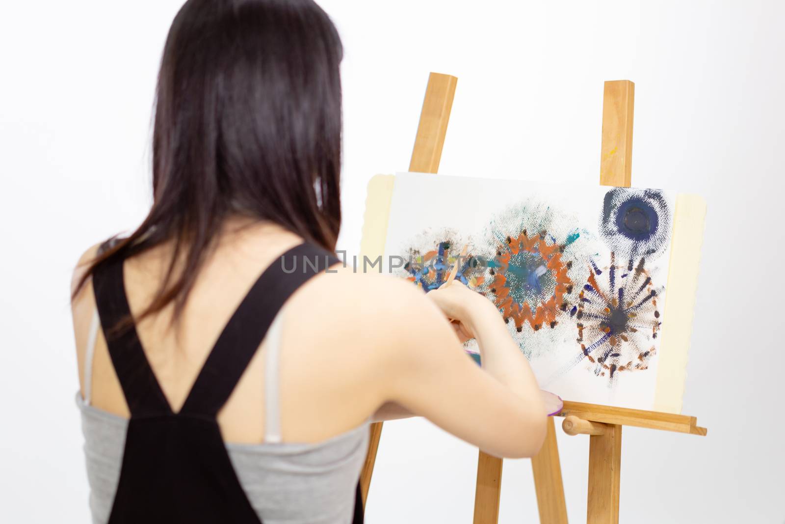 Female Asian artist painting on an easel