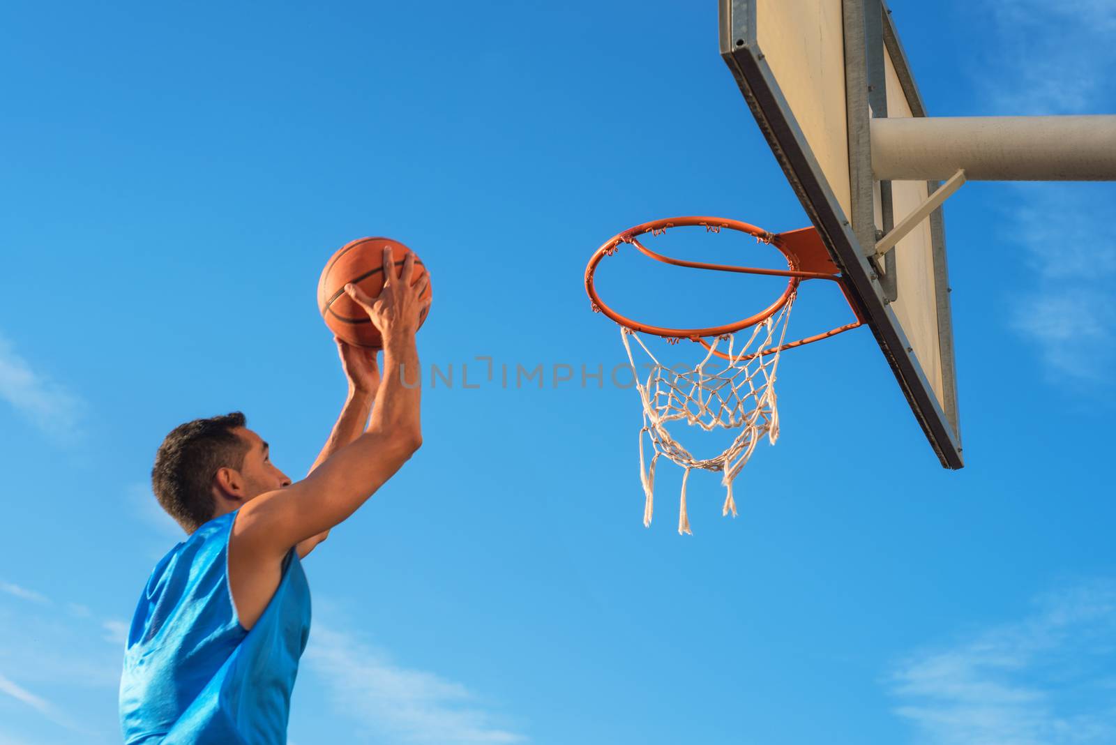 Street basketball athlete performing slam dunk on the court