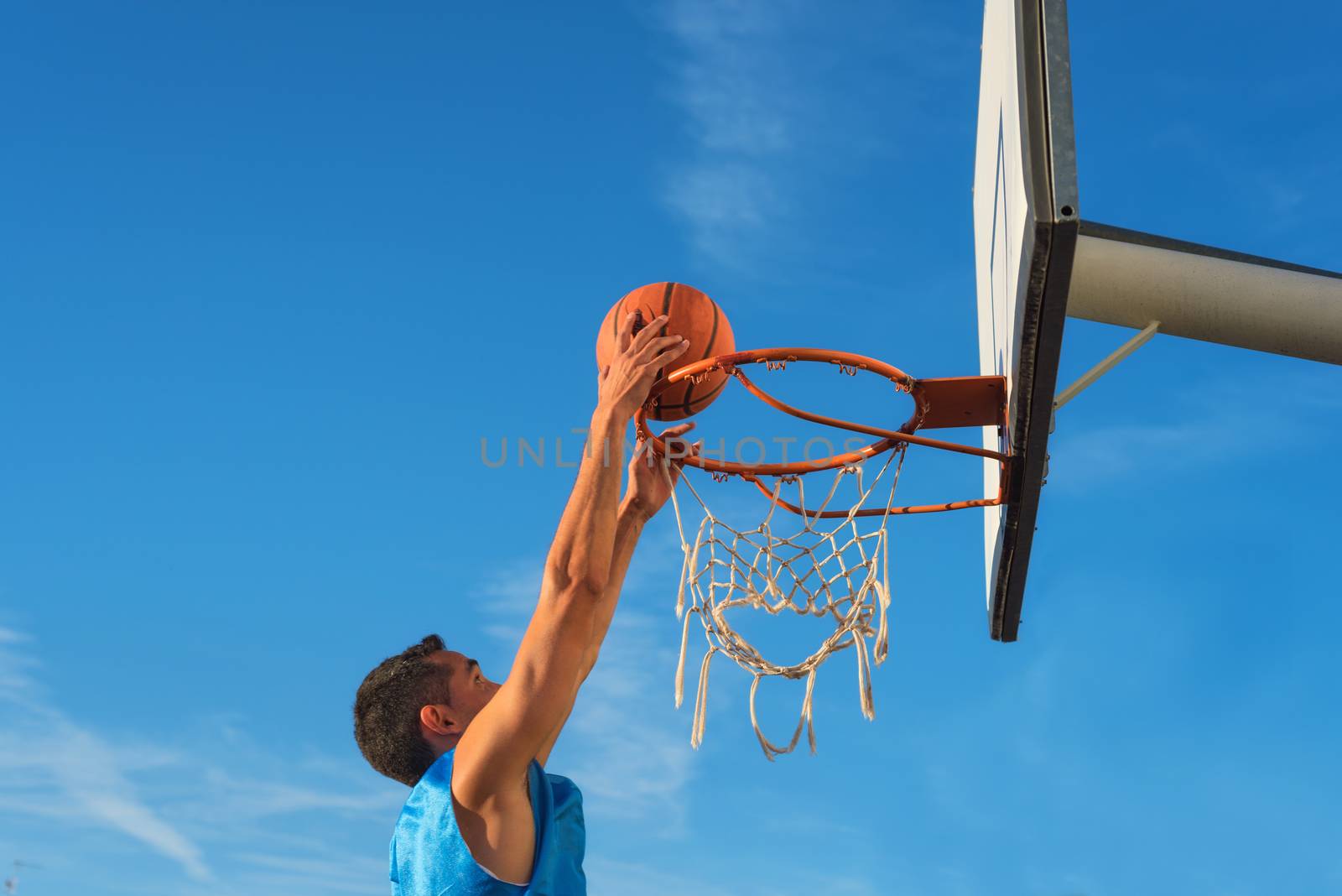 Street basketball athlete performing slam dunk on the court