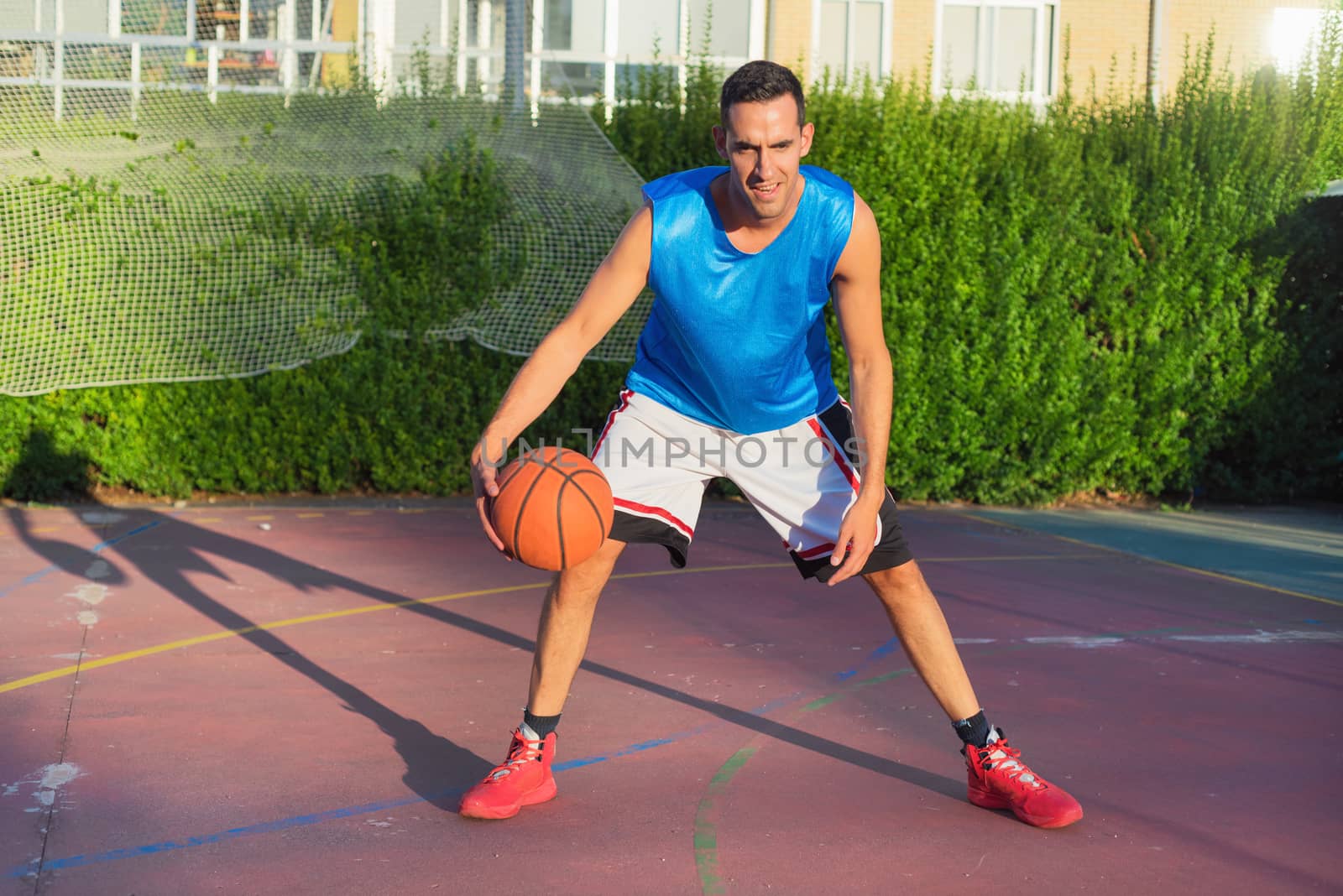 Young man athlete on basketball court dribbling by HERRAEZ