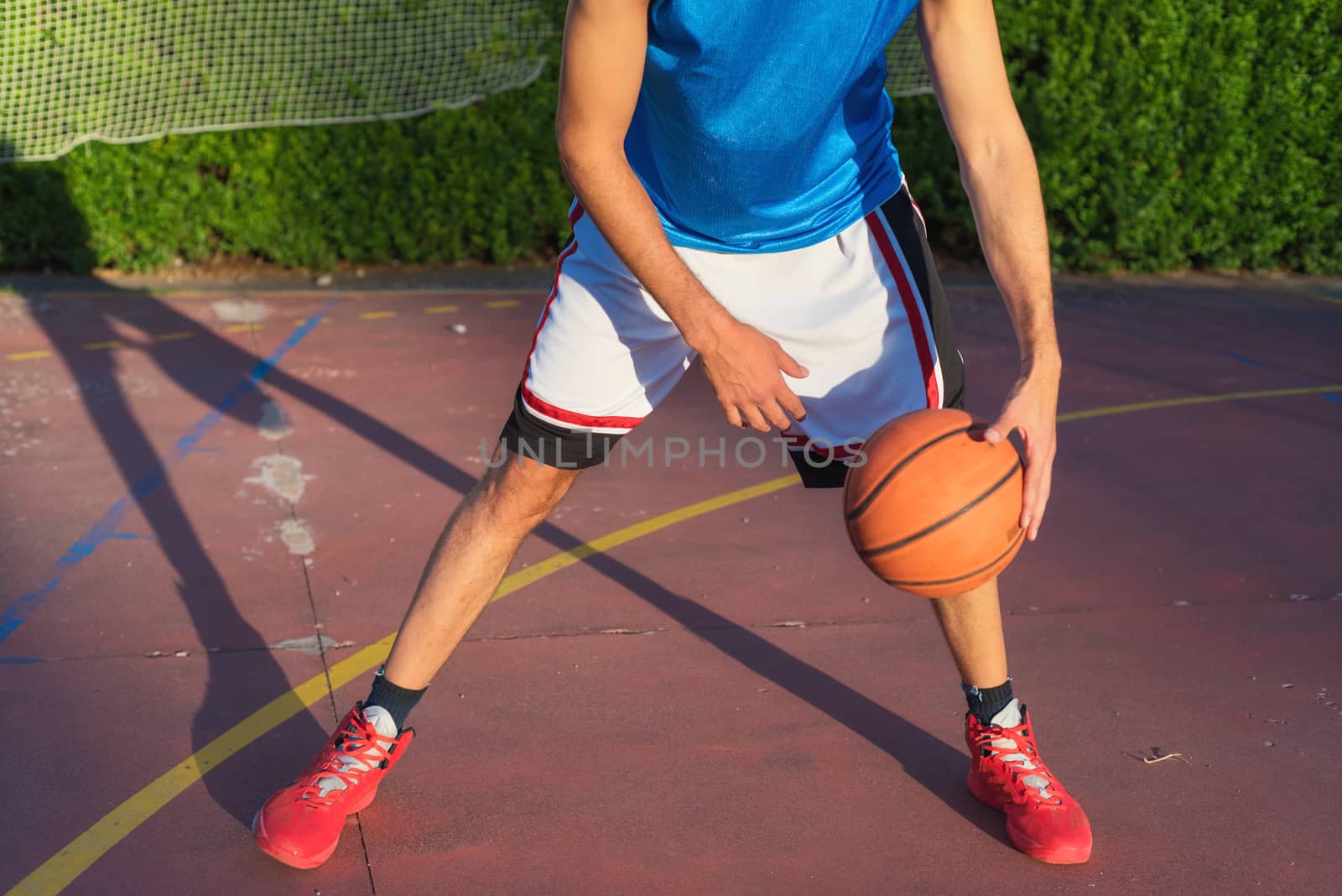 Young man athlete on basketball court dribbling by HERRAEZ