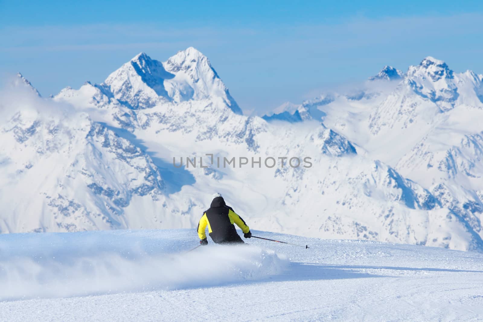 Skier skiing downhill in high mountains, rear view, Solden, Austria