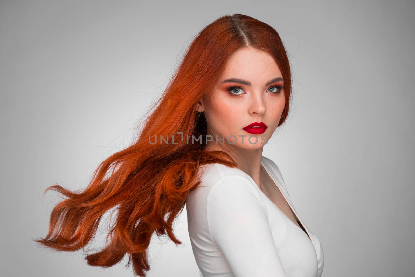 Gorgeous redhead girl with wavy hair beauty studio portrait
