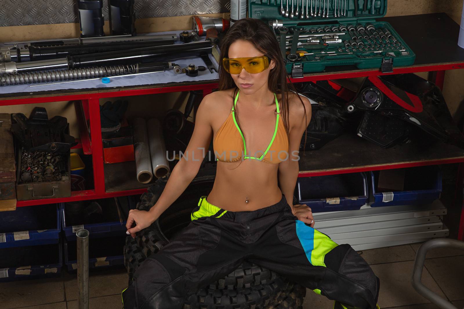 Girl in garage with motorcycle working with bike tires