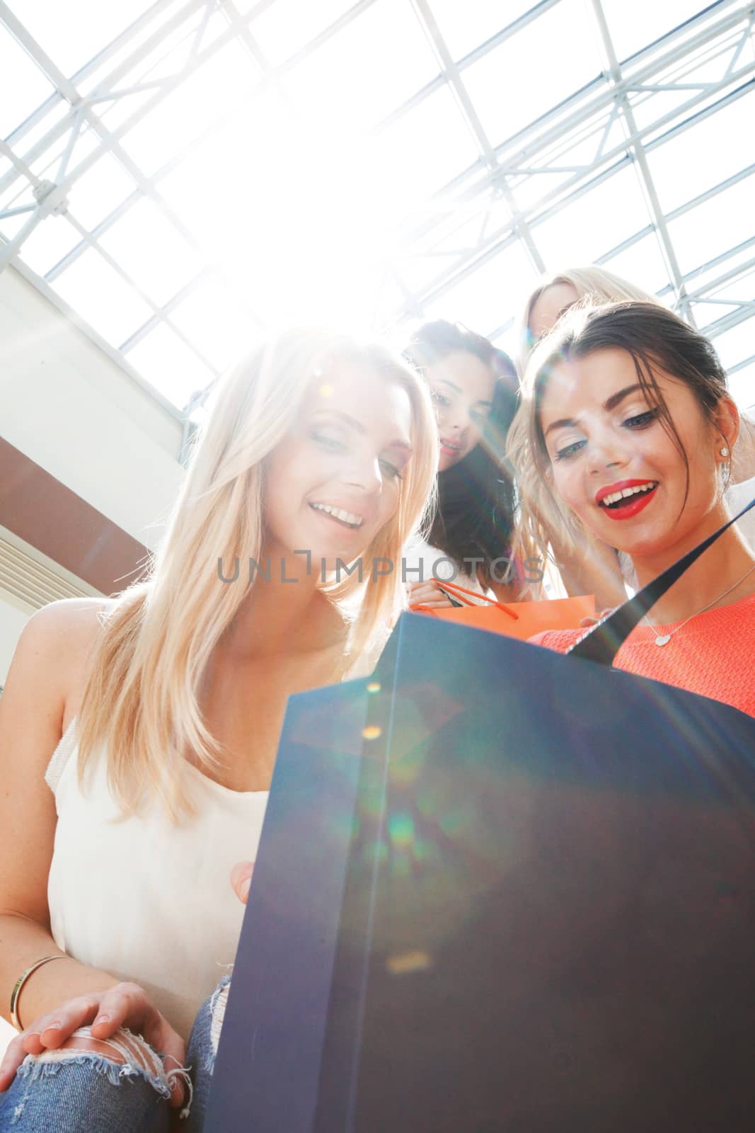 Beautiful female friends look into shopping bag at mall