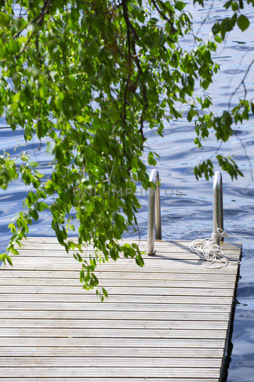 Wooden walkway jetty pier with railing for swimming in lake in Finland