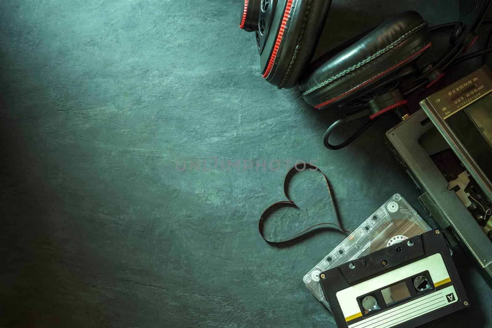 Cassette player and headphone on cement floor. Heart shape of cassette tape strip. Top view and copy space for text. Concept of music is the heart.