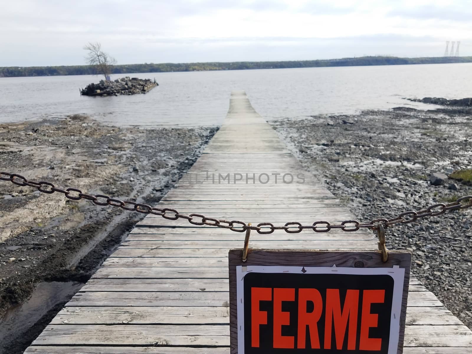 wooden boardwalk or pier with ferme or closed in French sign