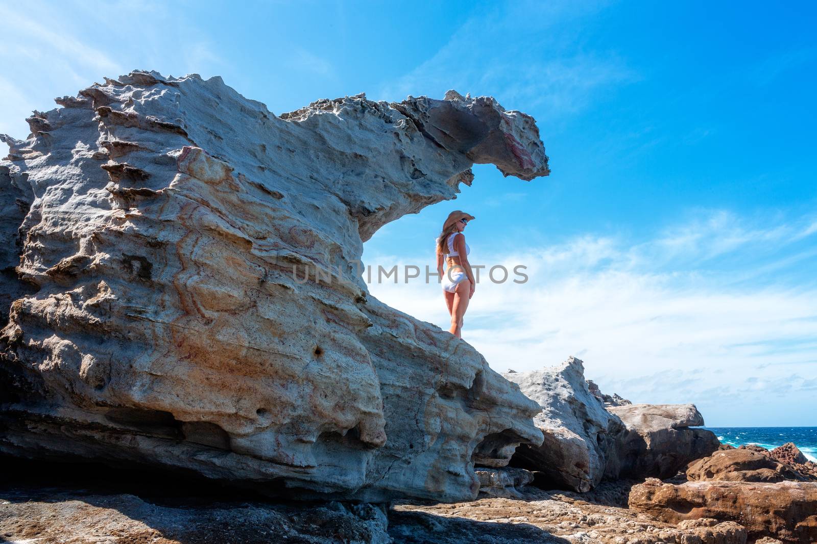 Woman standing in a sandstone formation by the ocean by lovleah