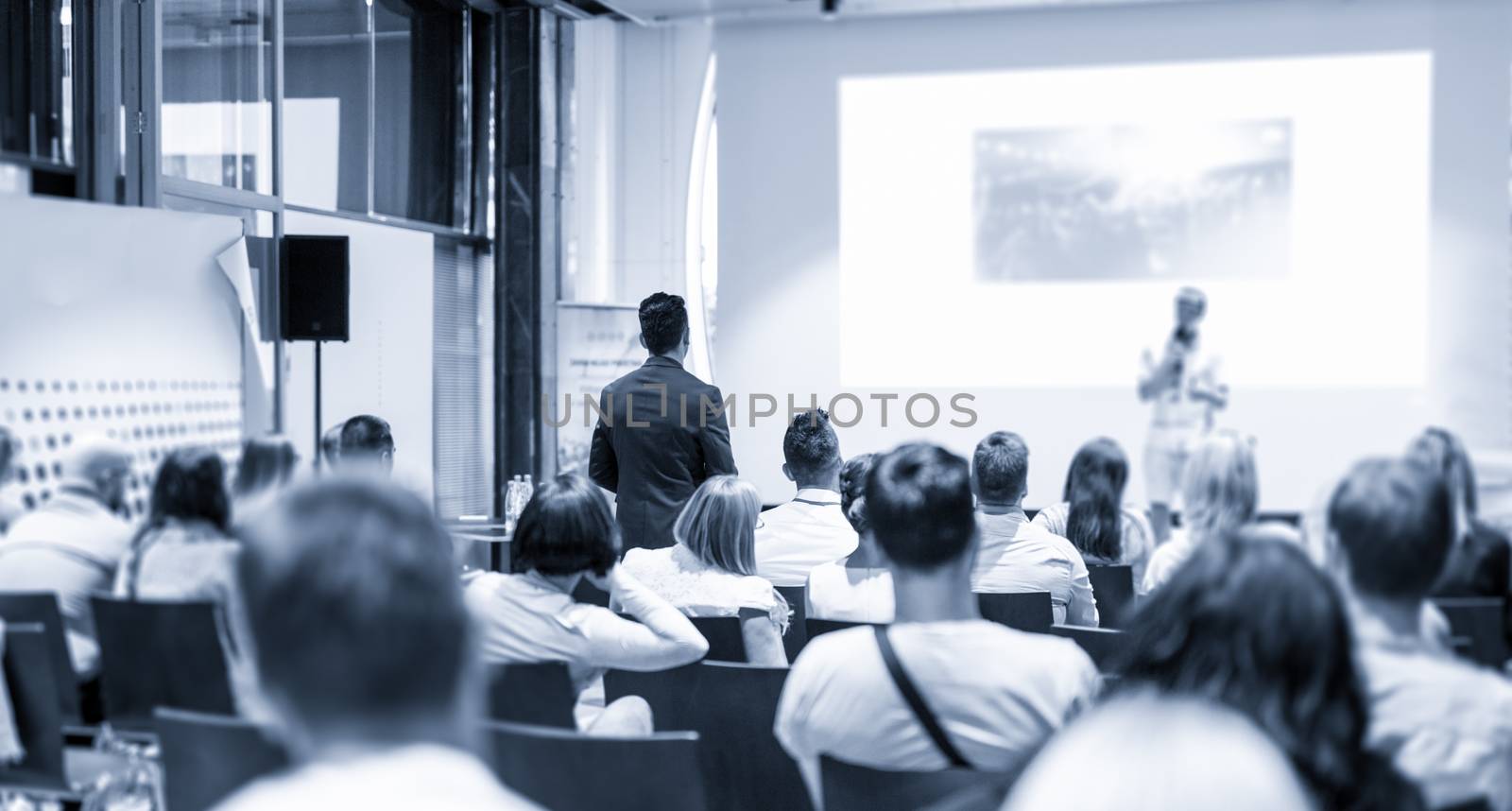 I have a question. Group of business people in conference hall. Businessman in audience standing and asking question to speeker. Conference and Presentation. Business and Entrepreneurship.