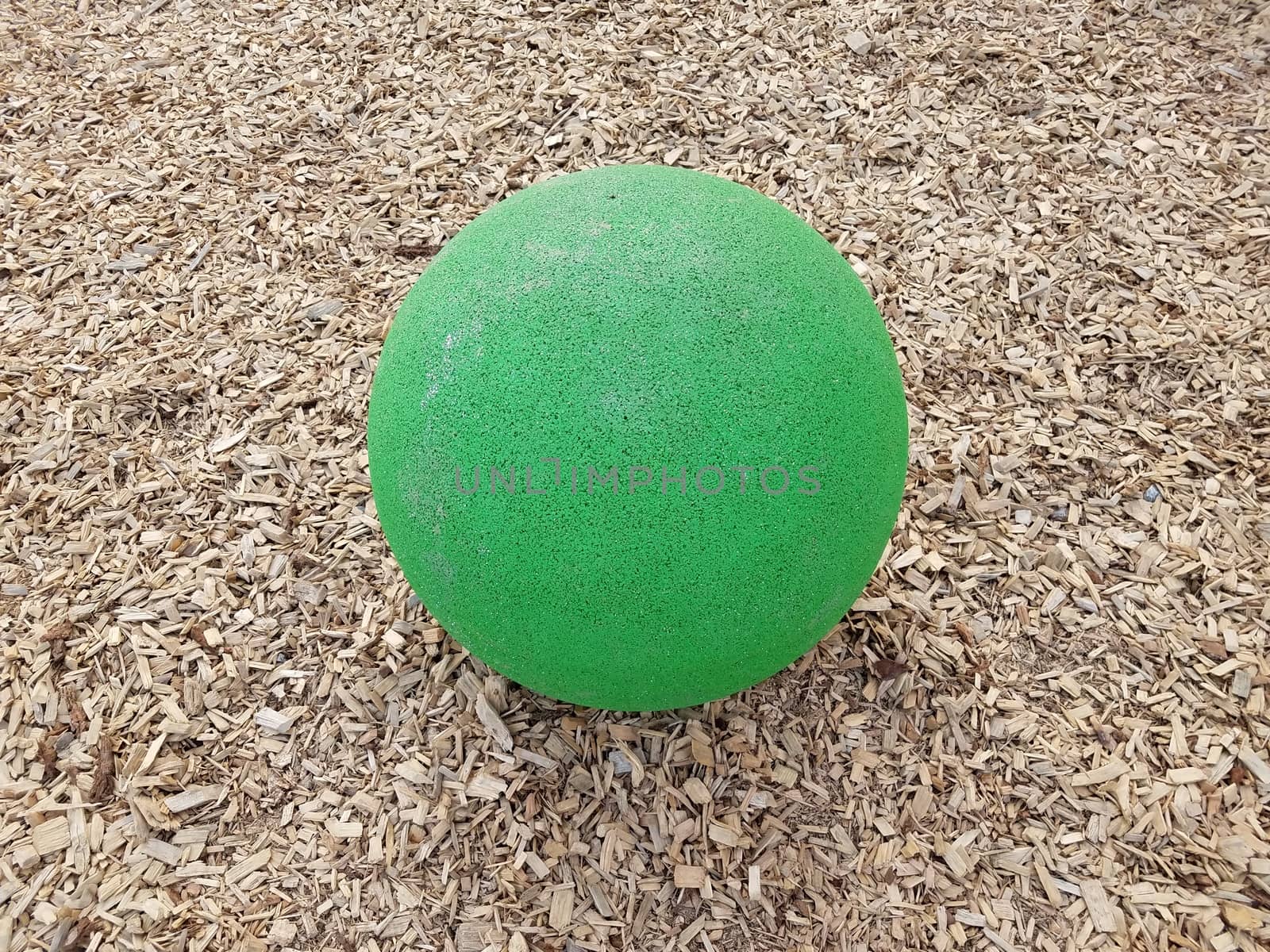 large green ball or sphere in brown mulch or wood chips
