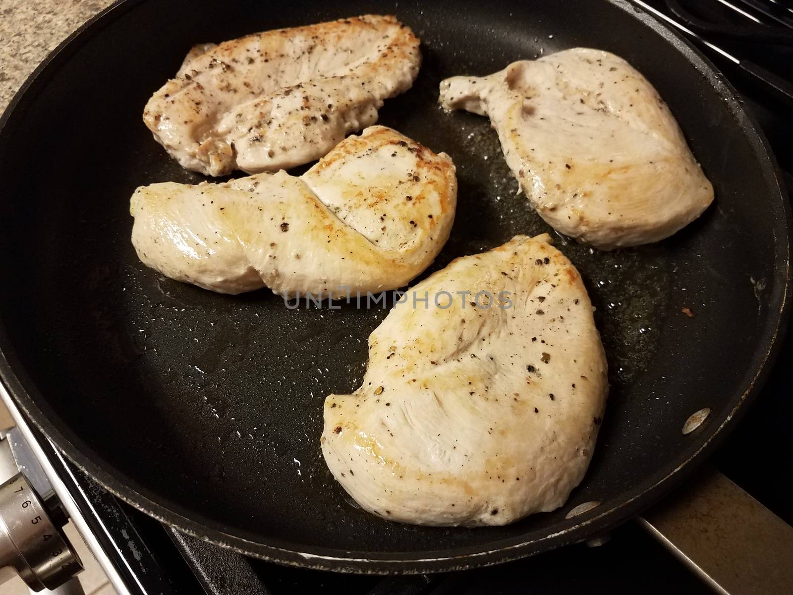 raw chicken breast meat cooking in frying pan with oil
