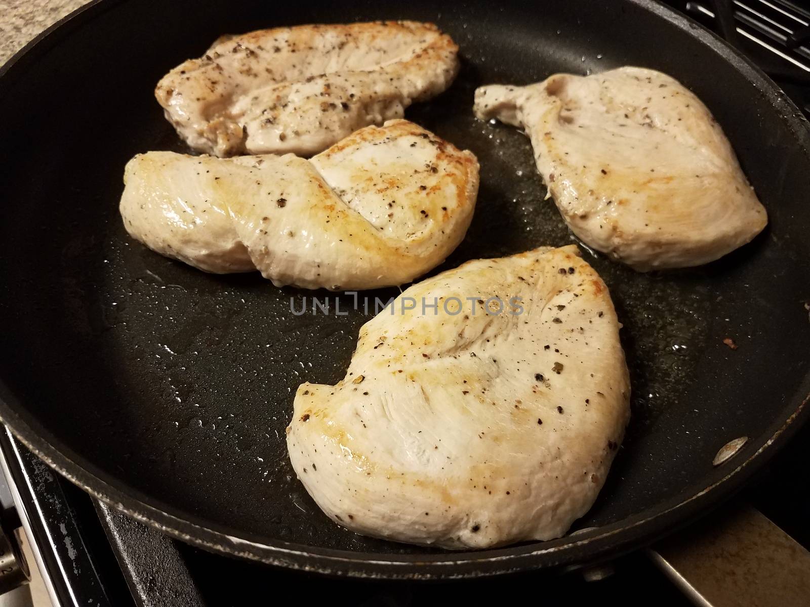 raw chicken breast meat cooking in frying pan with oil