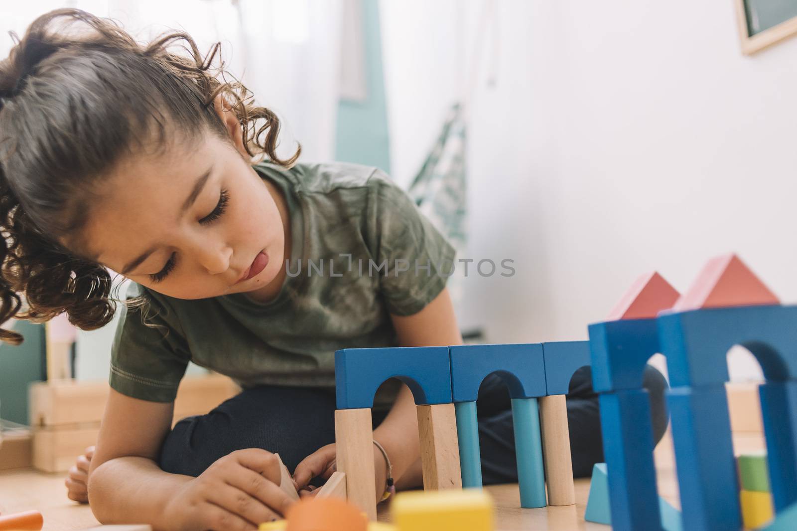 child little girl playing constructions on the floor with wooden building block toys at home or kindergarten, educational toys for creative children