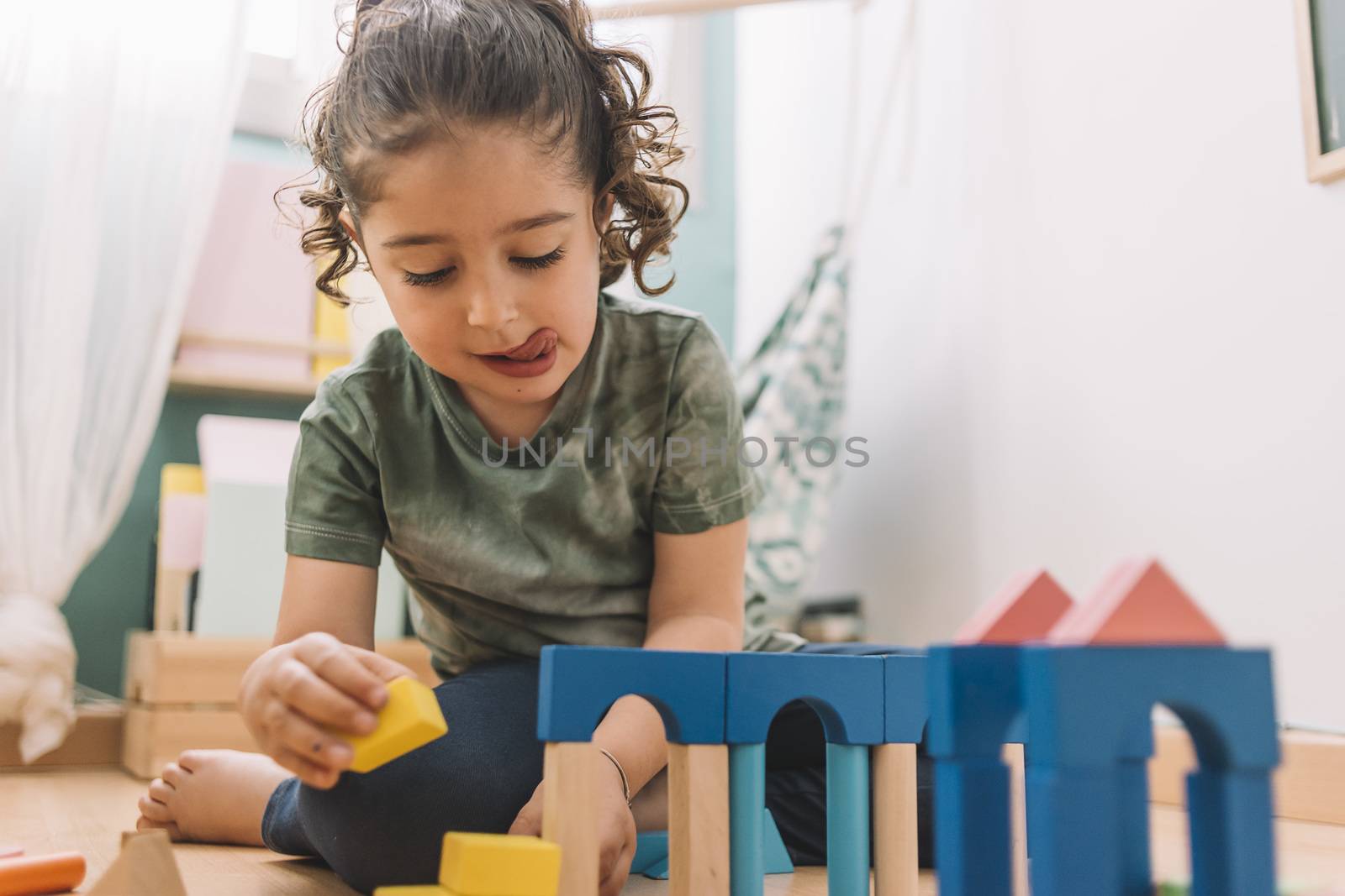 little girl playing constructions on the floor with wooden building block toys at home or kindergarten, educational toys for creative children