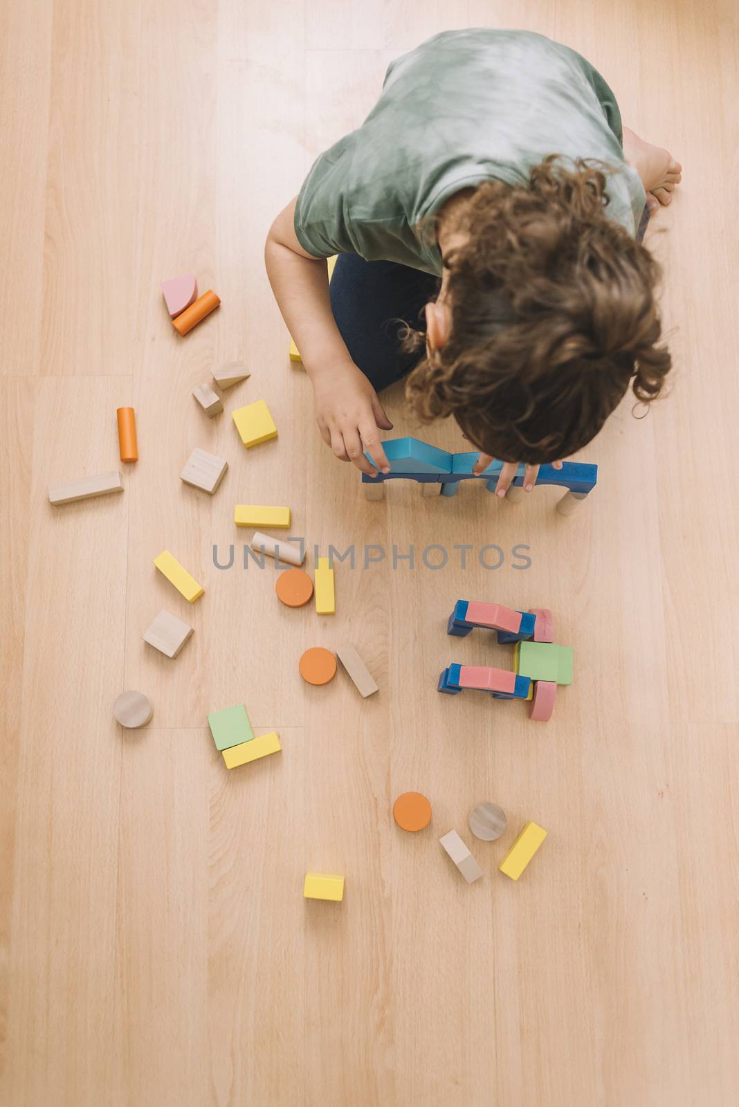 top view of a little girl playing in the floor with colorful wooden building block toys at home or kindergarten, educational toys for creative children