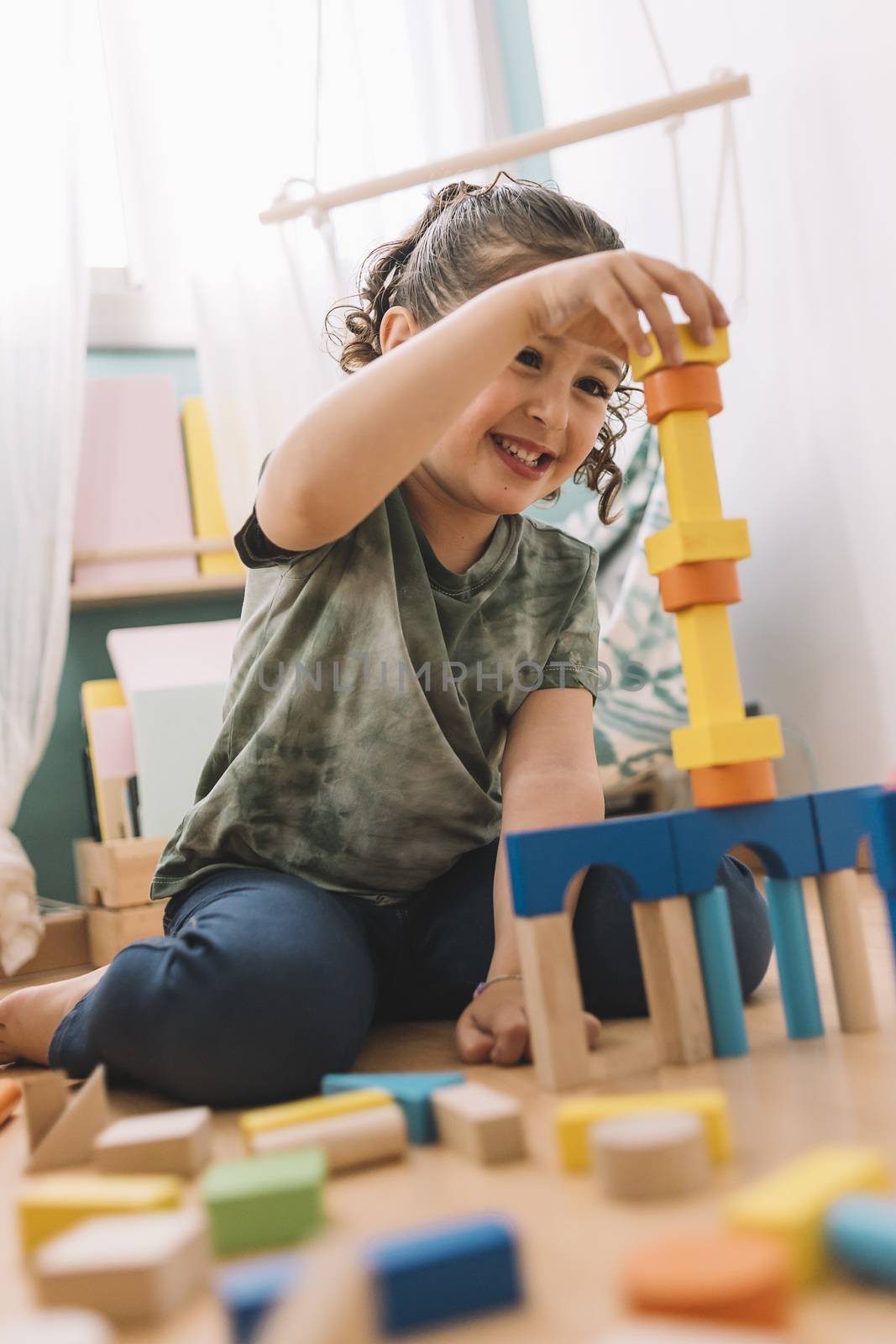 smiling little girl playing happy in the floor with colorful wooden building block toys at home or kindergarten, educational toys for creative children