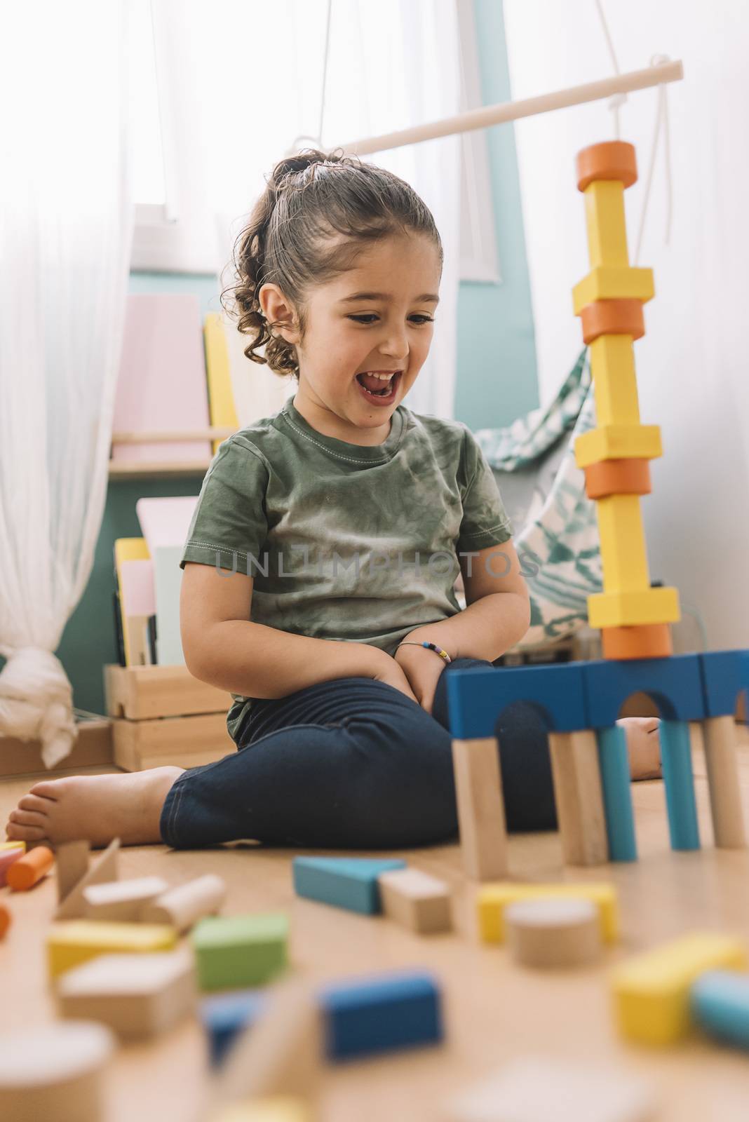 happy little girl playing funny in the floor with colorful wooden building block toys at home or kindergarten, educational toys for creative children