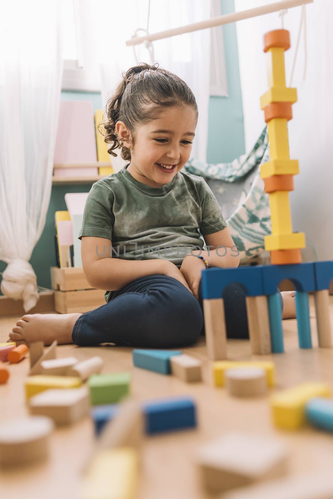 smiling little girl playing happy in the floor with colorful wooden building block toys at home or kindergarten, educational toys for creative children