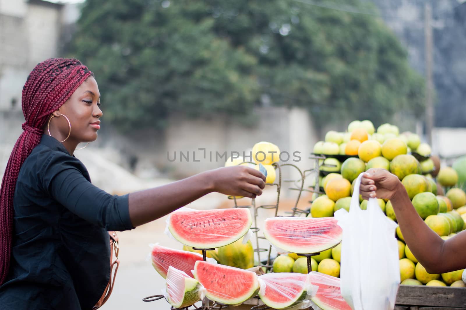 young woman gives a banknote to the vendor at street fruit market.