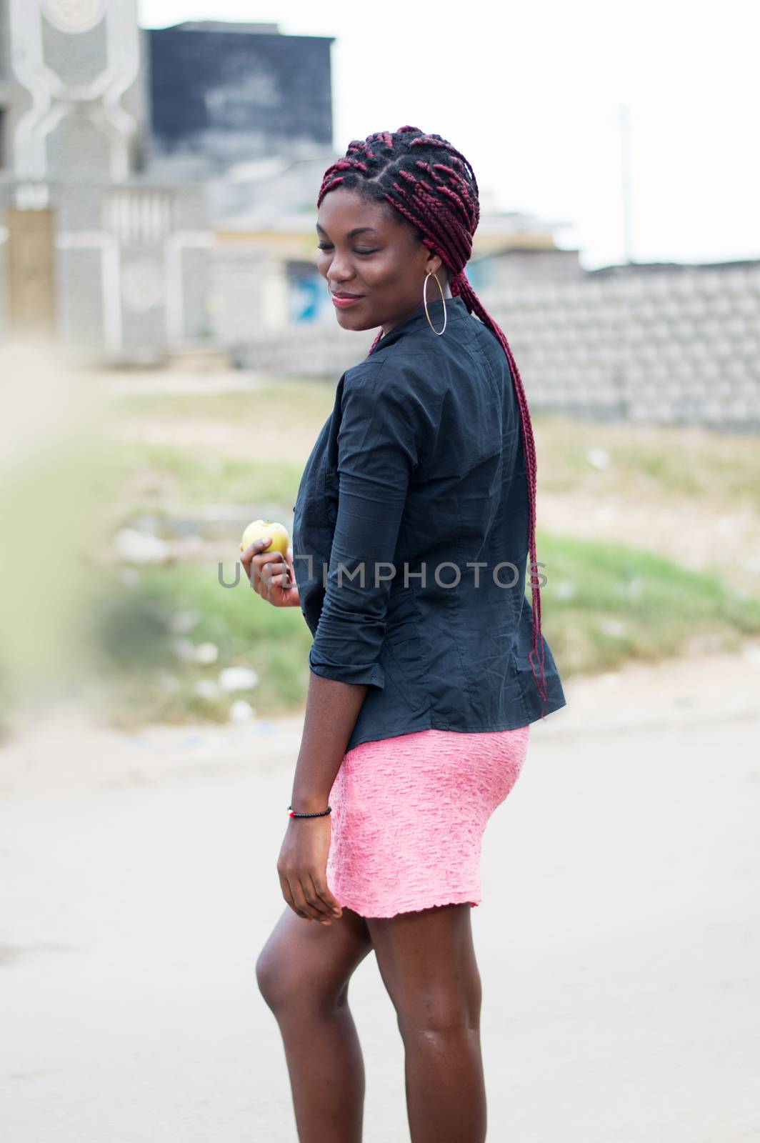 young woman holding an apple on the edge of the road.