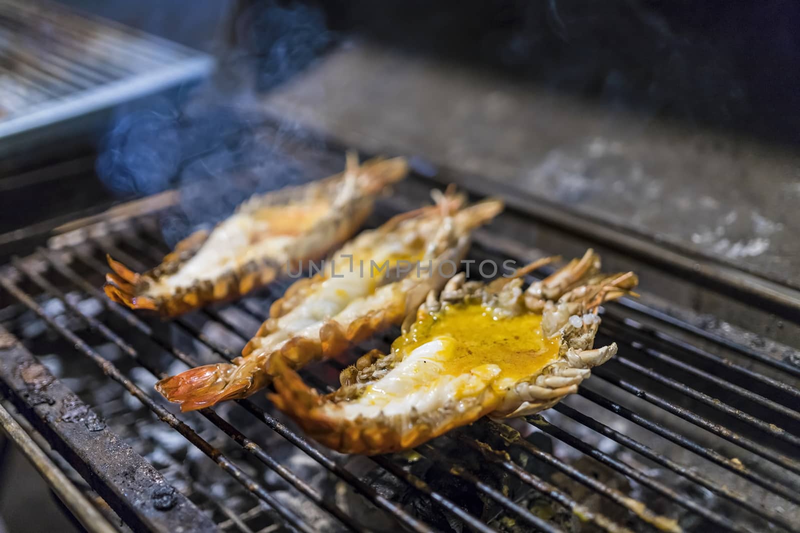 3 Large shrimps grilling on the grill. Smoke rising at night. Favorite Thai food. Selective focus.