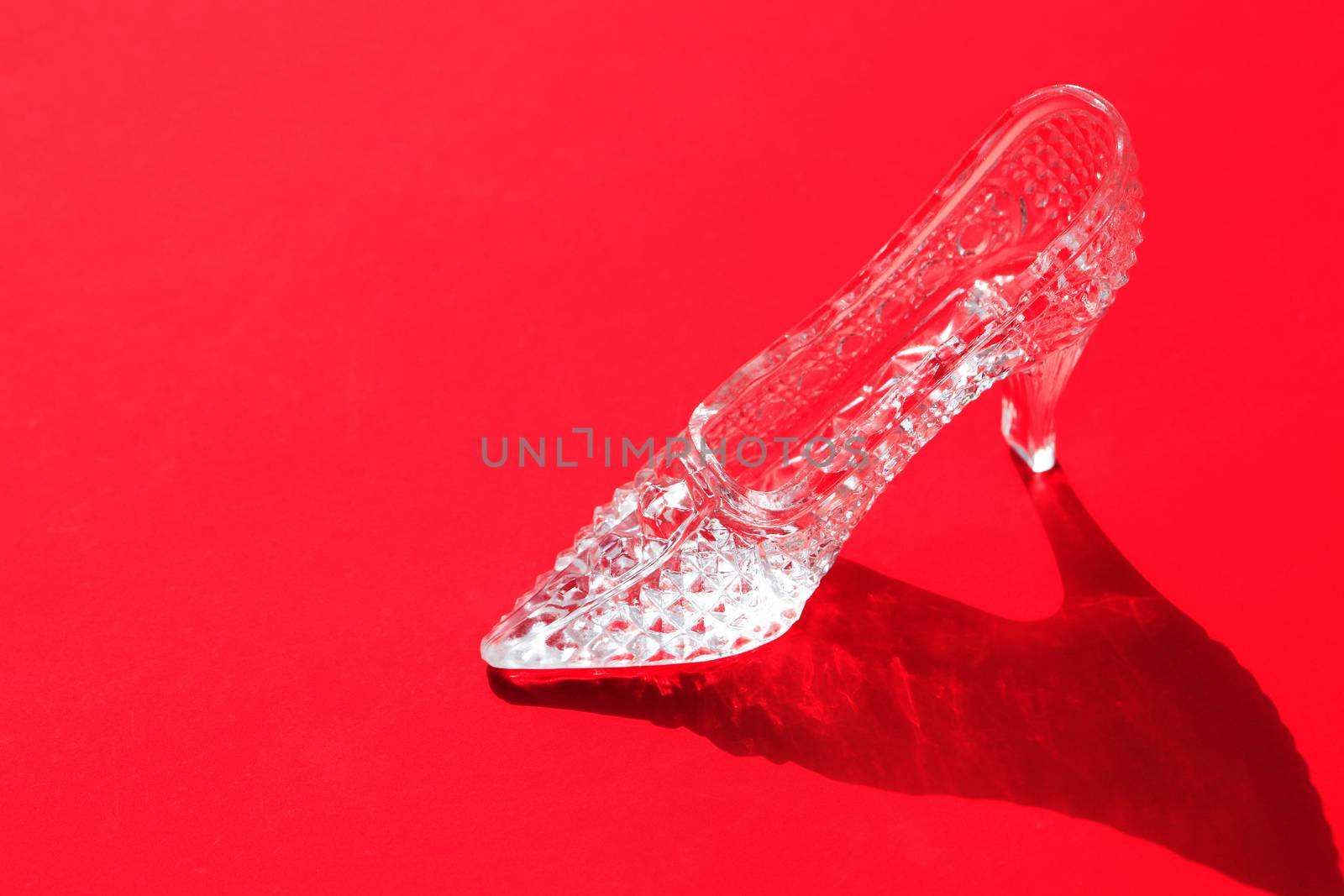 One nice glass slipper on red background with shadow