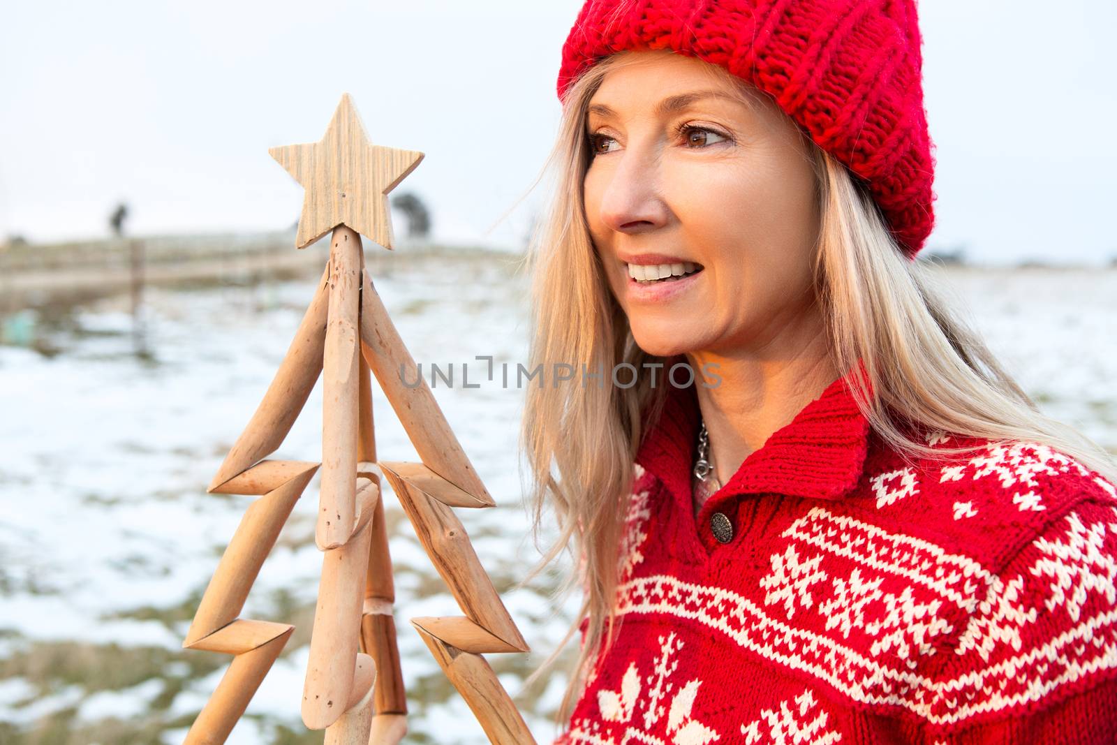 Woman holding a timber Christmas tree in a snowy landscape in Australia. Christmas season, Christmas in July