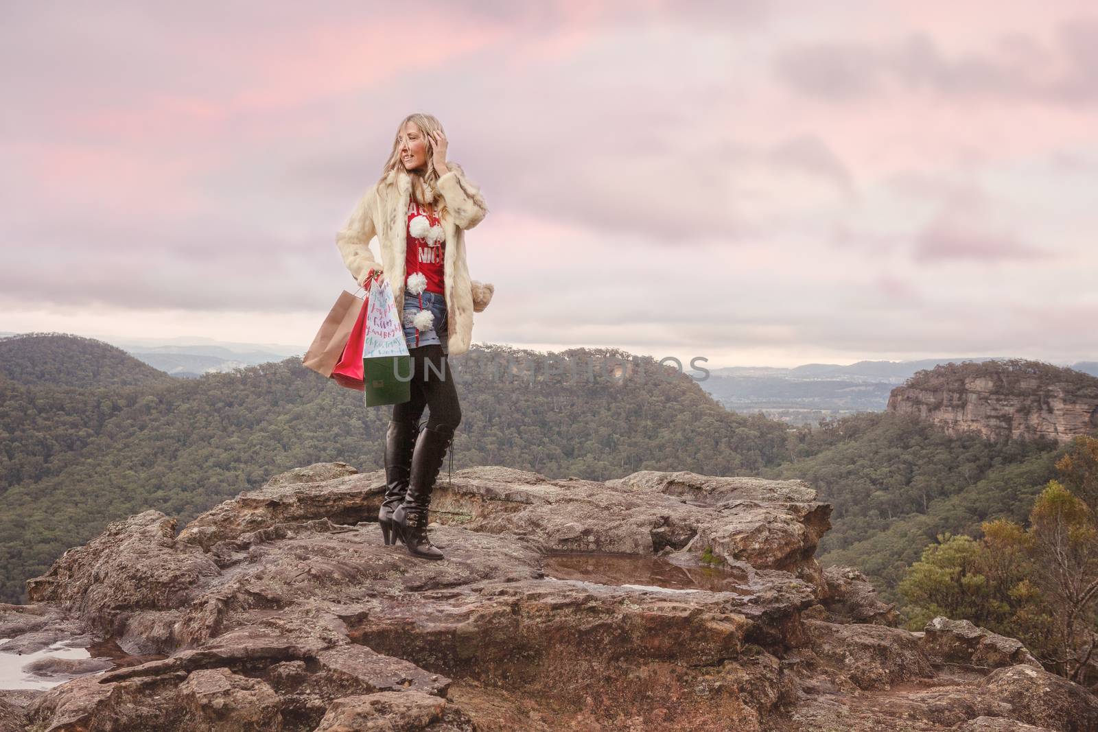 Christmas in July, Christmas in Blue Mountains, Eclectic  woman wearing coat and long boots carrying gift or retail shopping bags, Christmas theme with Blue Mountains backdrop