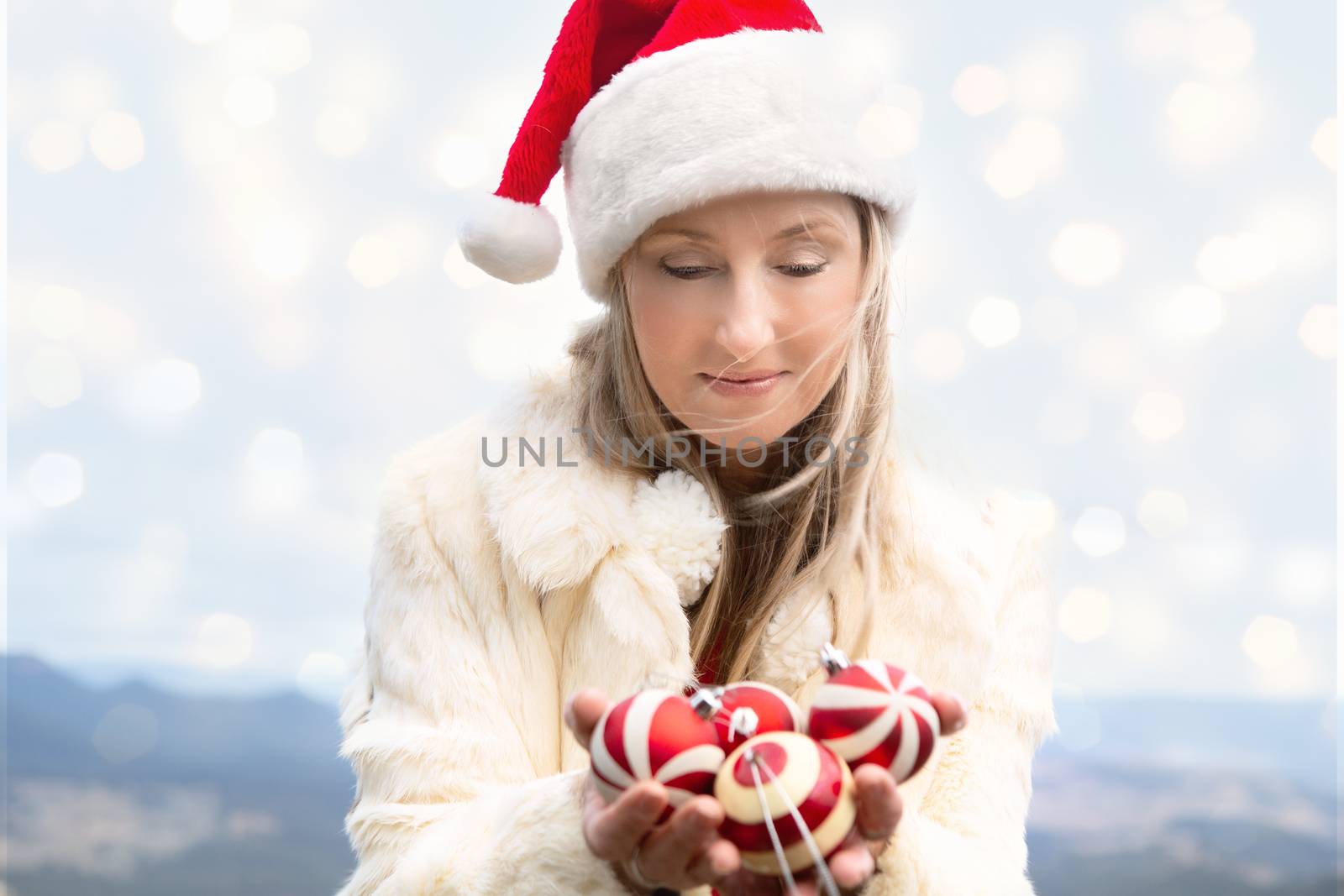 Woman in warm winter jacket cupping a handful of Christmas baubles with a soft bokeh backdrop of Blue Mountains and valley. Suitable for Christmas or holiday themes