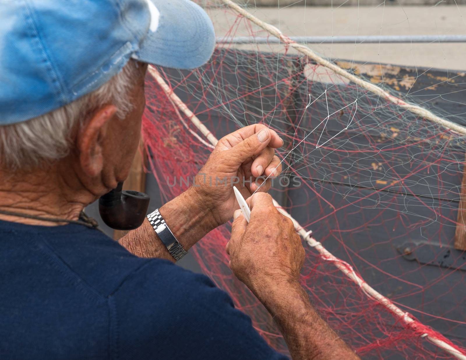 Senior fisherman repairs fishing net by Robertobinetti70