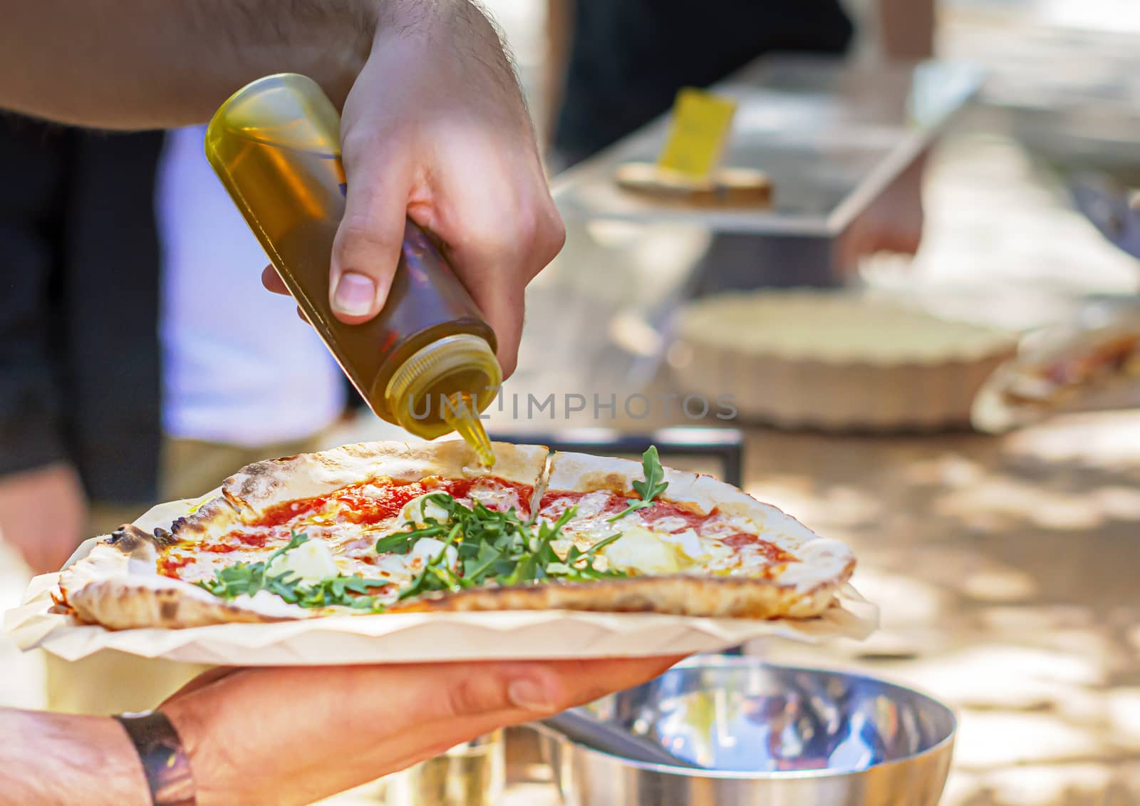 A male pouring olive oil to season a pizza. Italian cuisine. traditional Italian recipe.