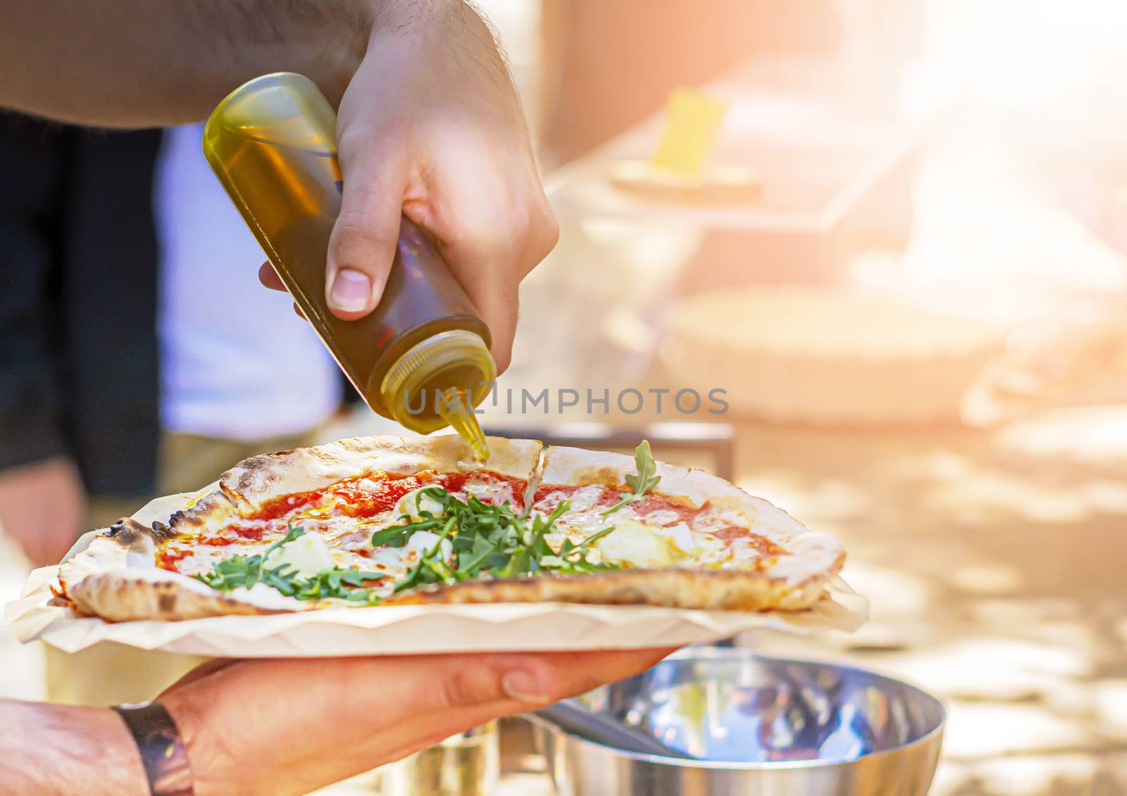 A male pouring olive oil to season a pizza. Italian cuisine. traditional Italian recipe.