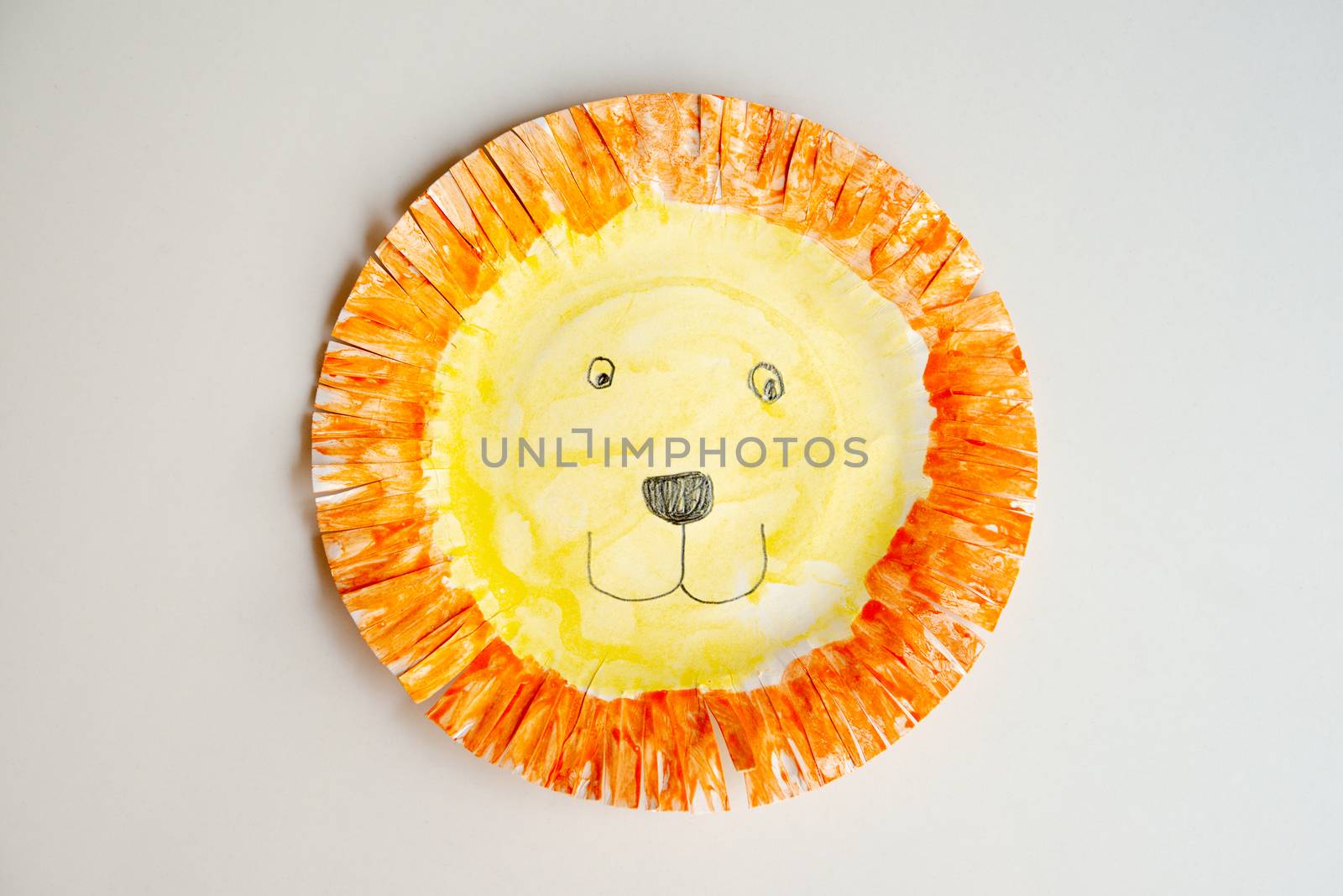 Child artwork, handmade lion mask on plain background.
