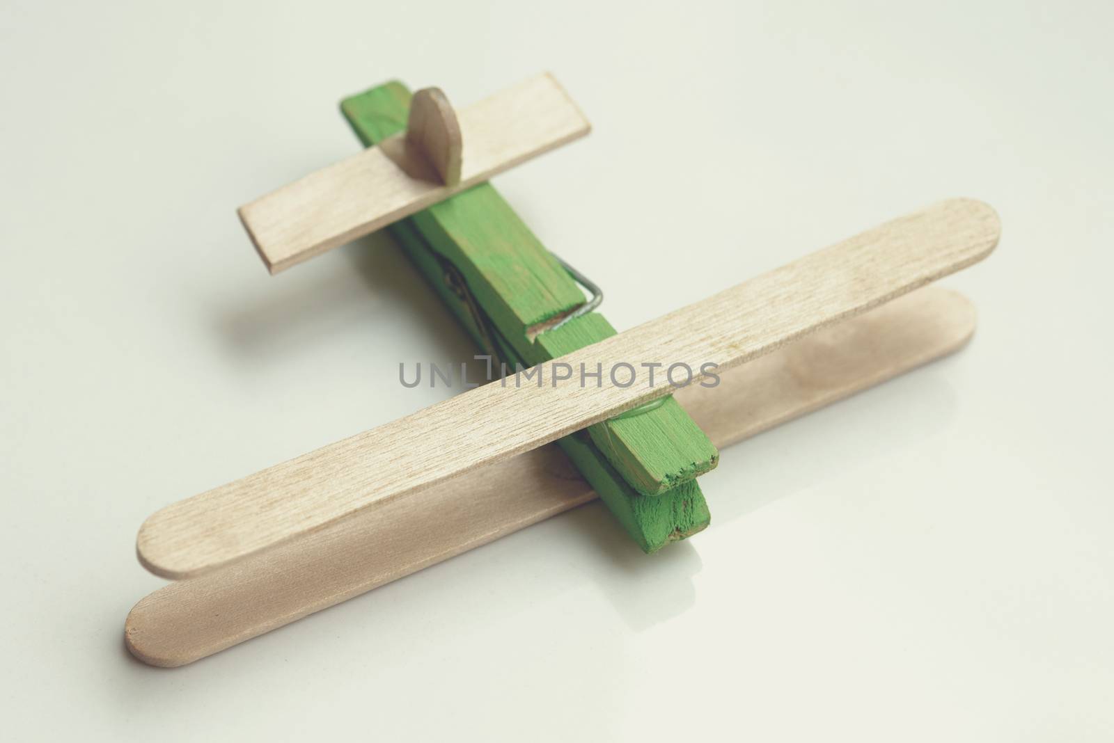 Child artwork, popsicle stick made plane on plain background.