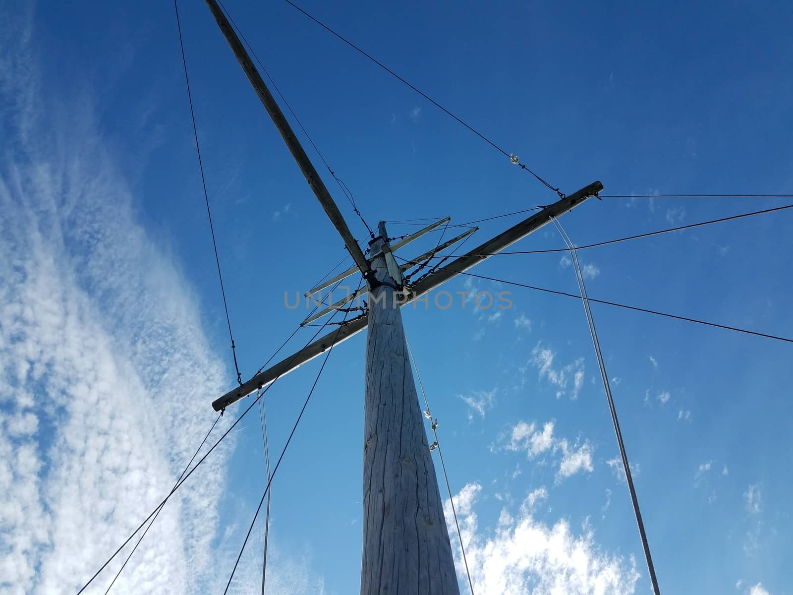 wooden pole boat mast with cables and blue sky
