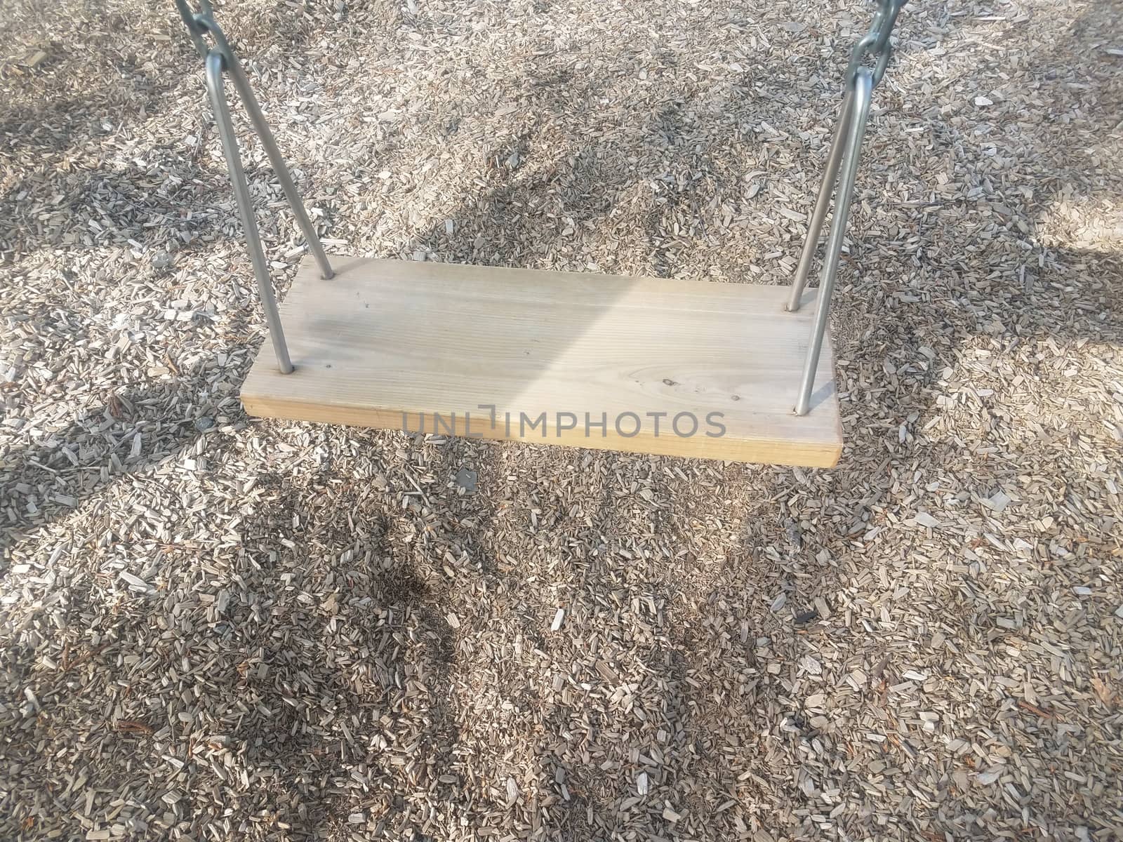 swingset with wooden seat on swing and brown mulch or wood chips