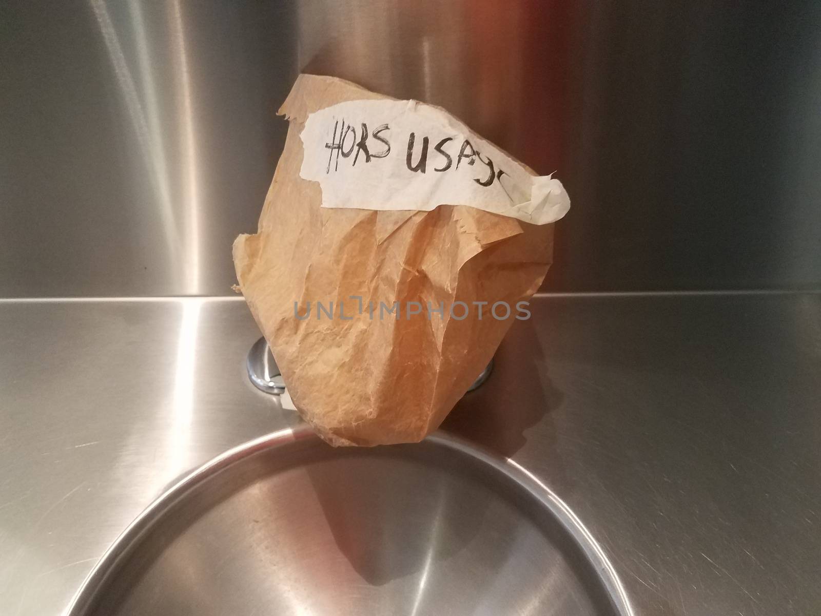 metal sink in bathroom with out of order sign in French and brown paper bag