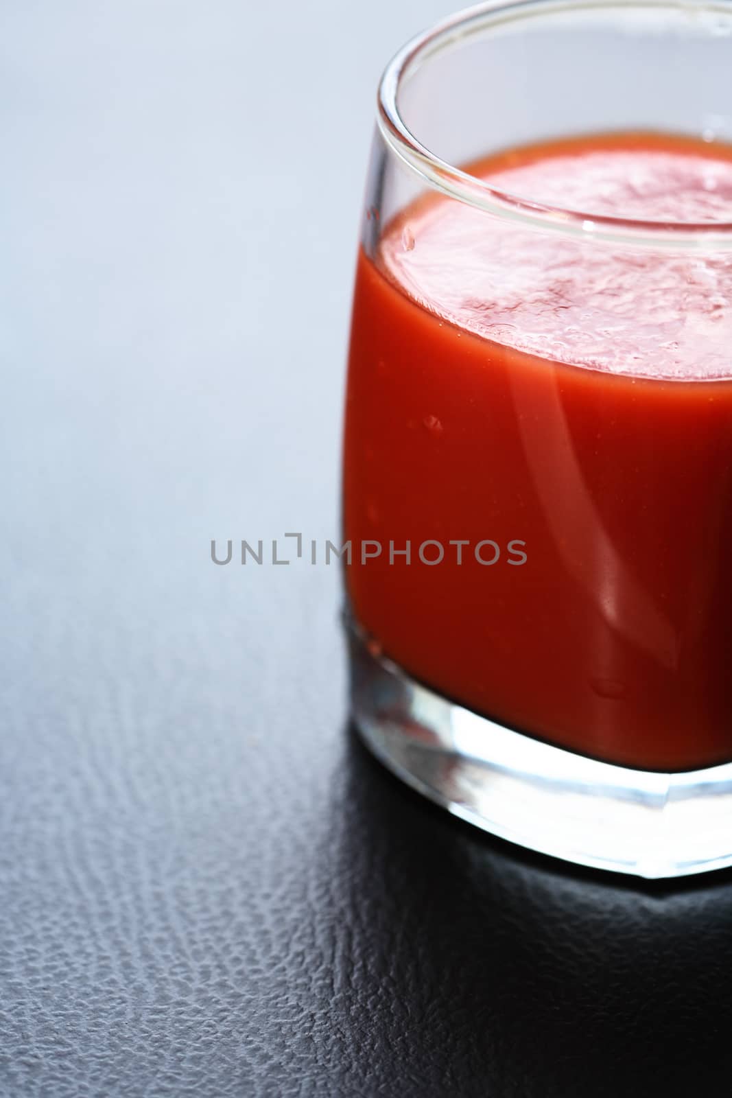 Full glass of tomato juice on nice gray background