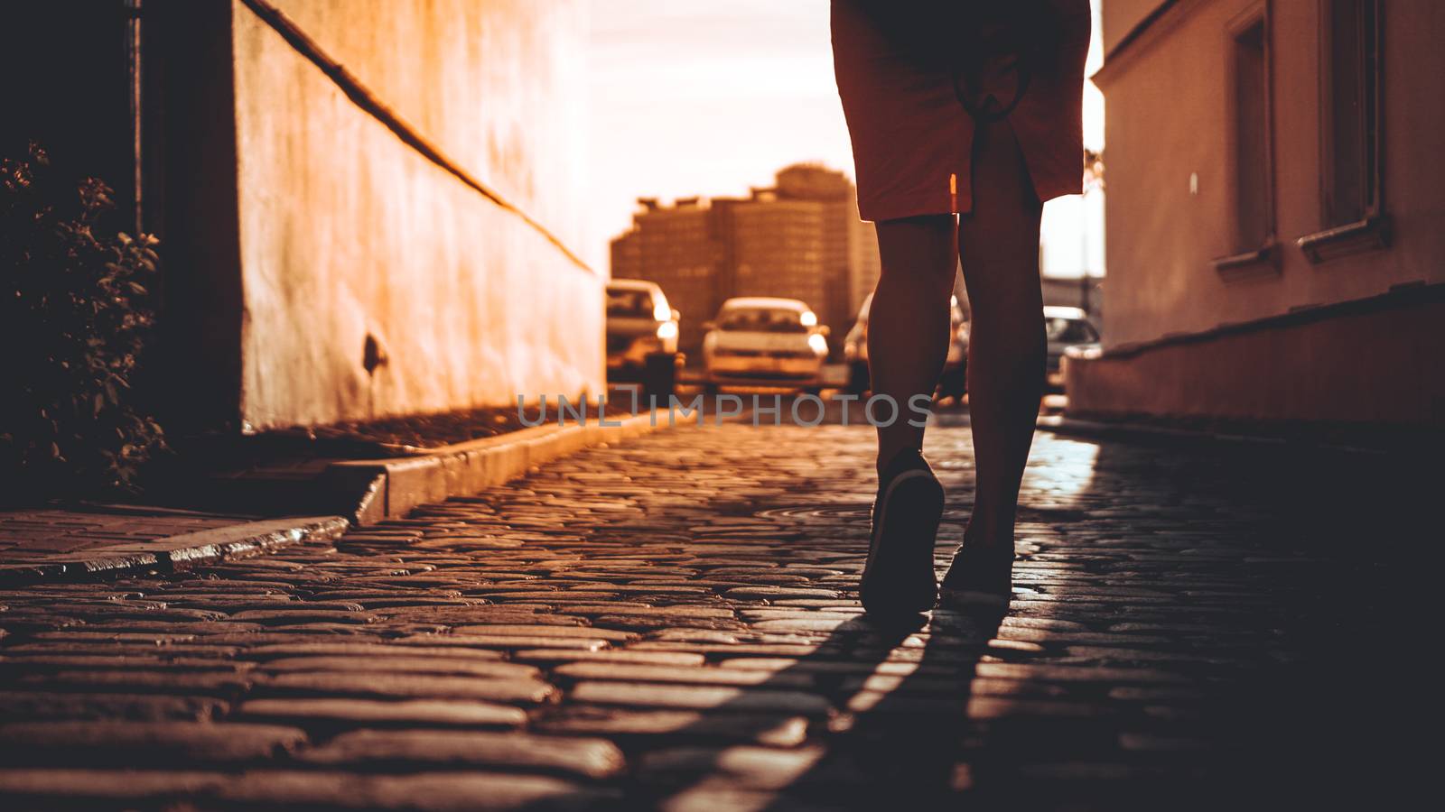 Silhouette of a girl who, in the rays of the sun, walks on a stone pavement in a European city, the concept of a happy trip, a holiday in Europe