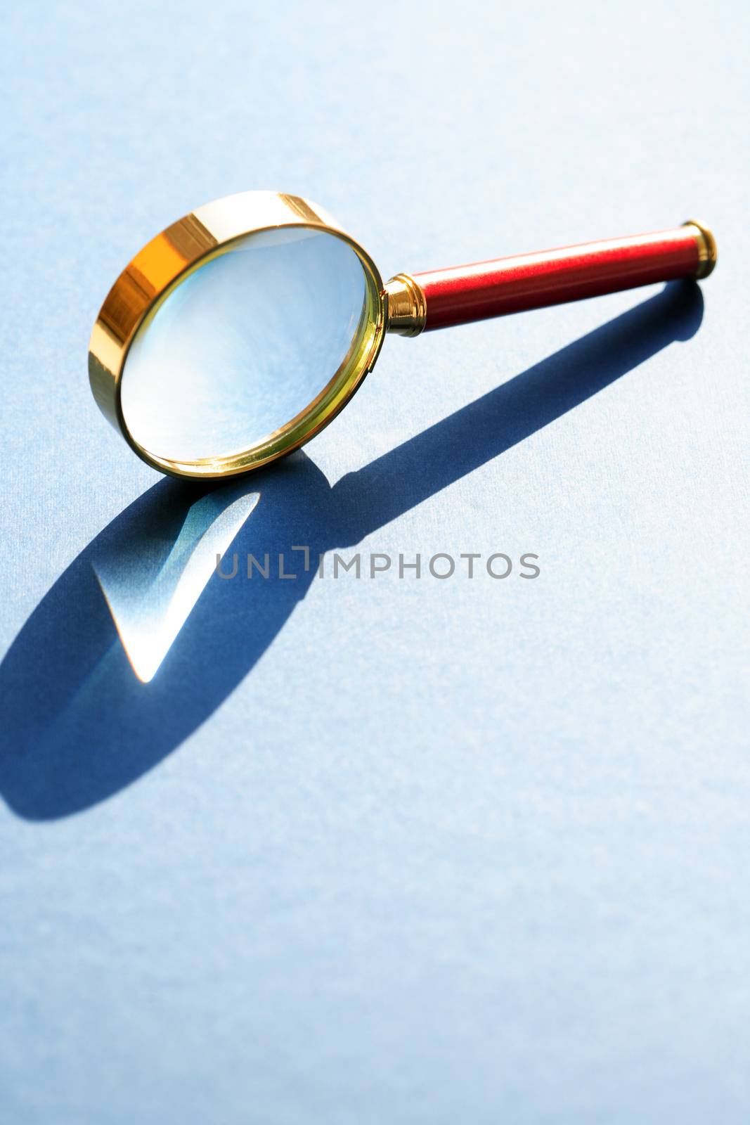 Nice retro magnifying glass under sunlight on gray background