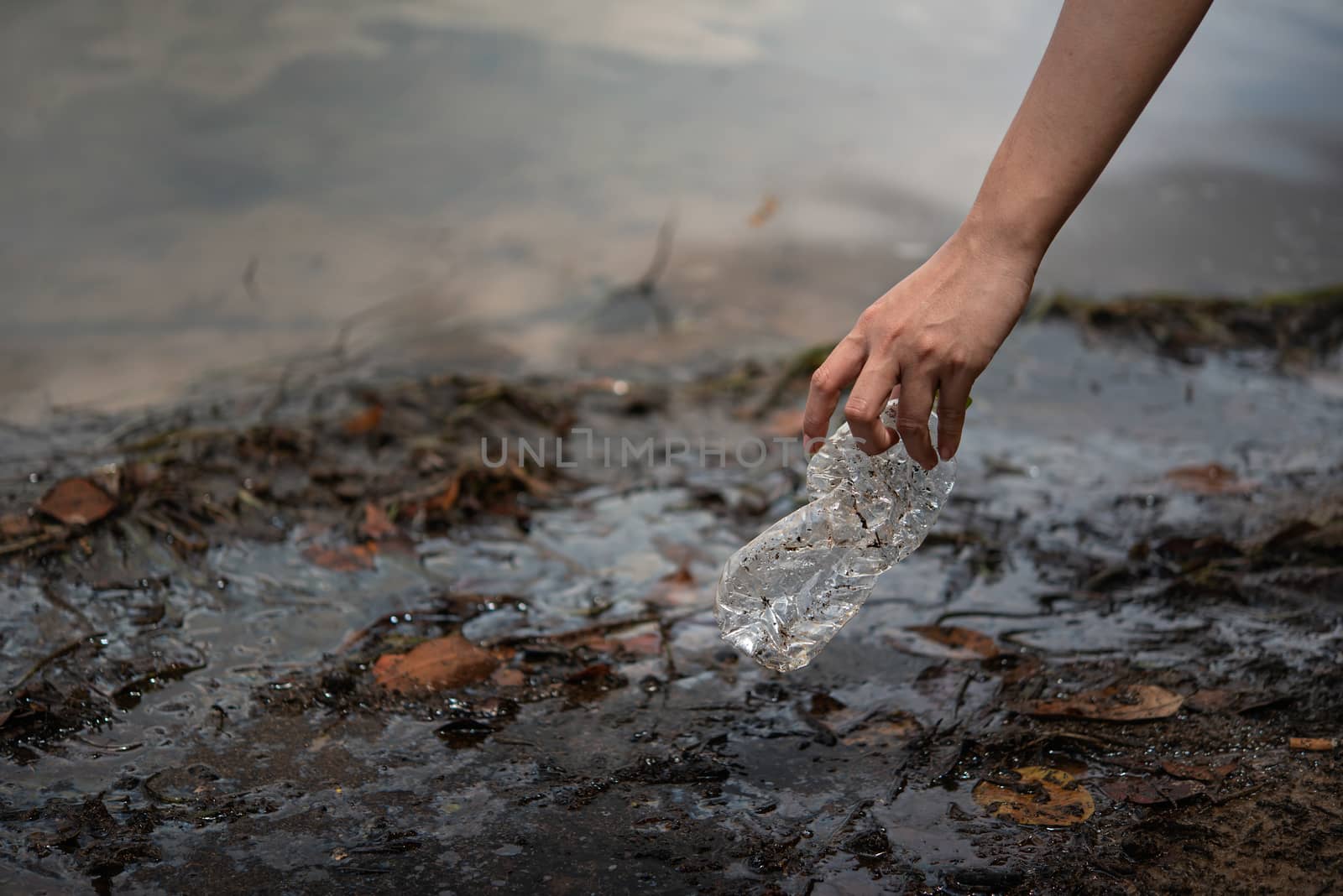 hand pick up plastic bottle from water by rakratchada
