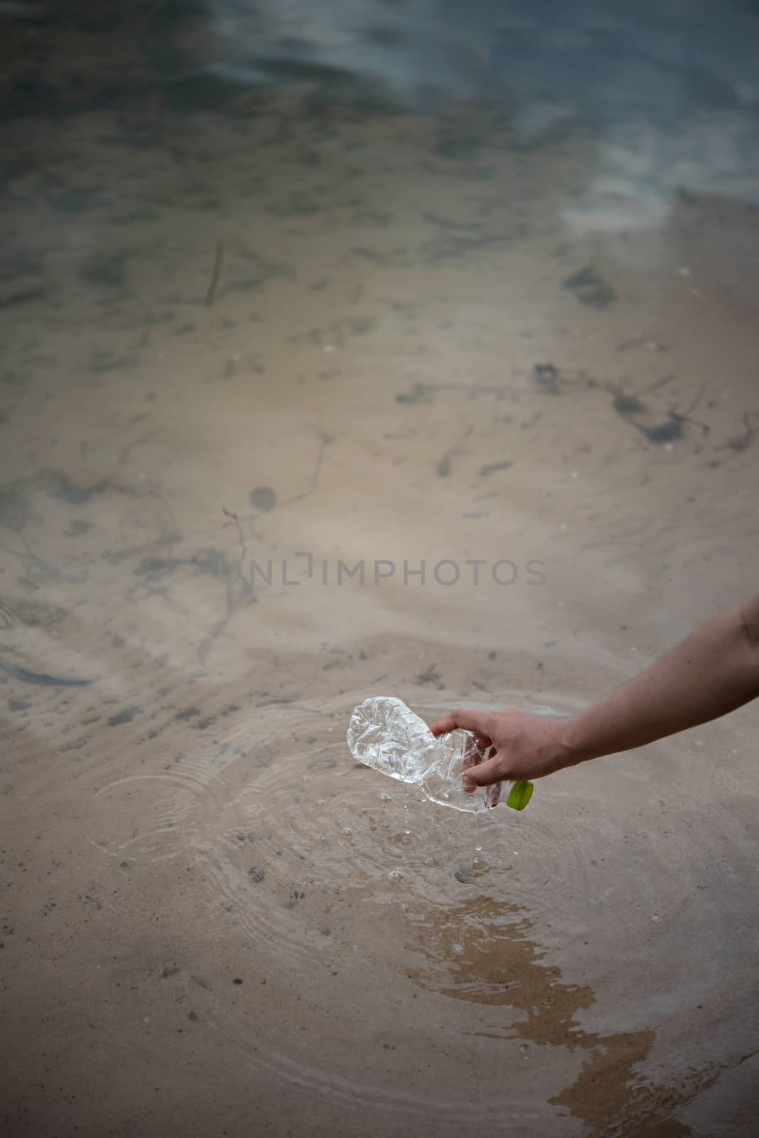 hand pick up plastic bottle from water. save environment and beat plastic pollution , Selective focus